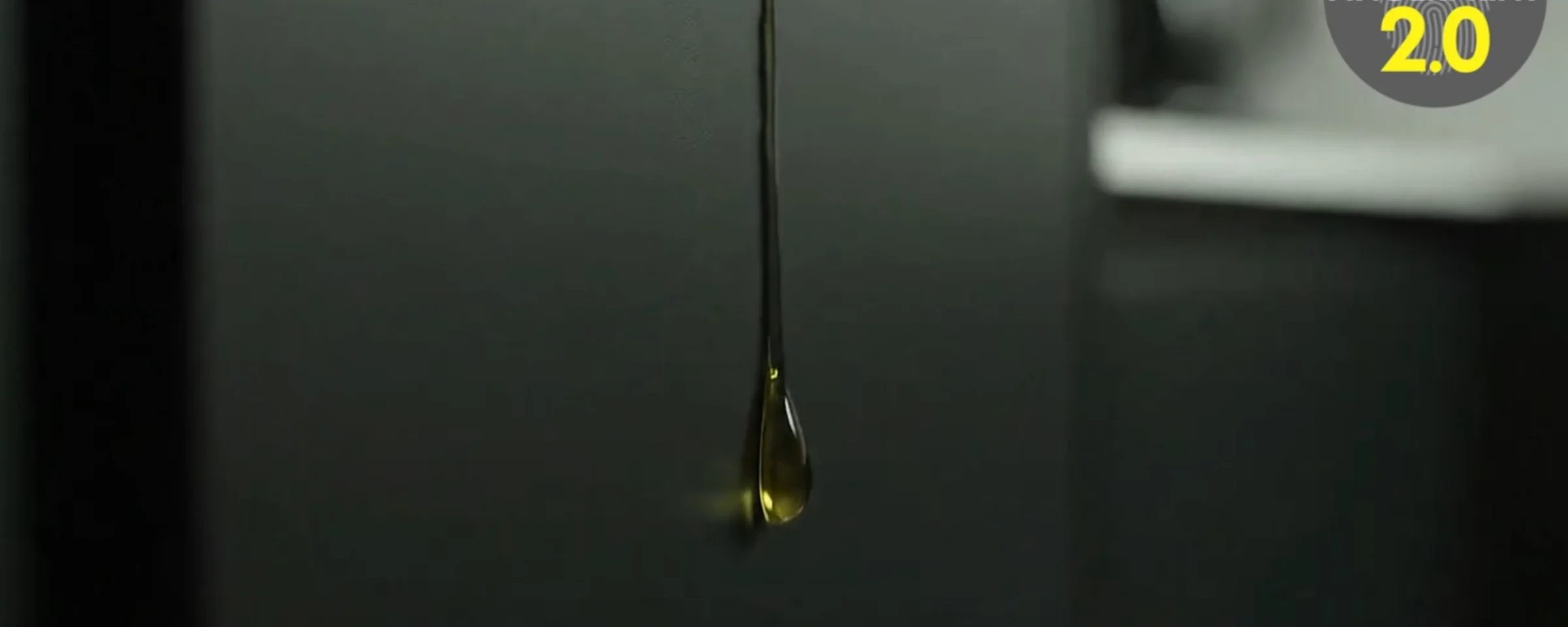 Eine Öltropfen fließt an einer schwarzen Oberfläche hinunter.