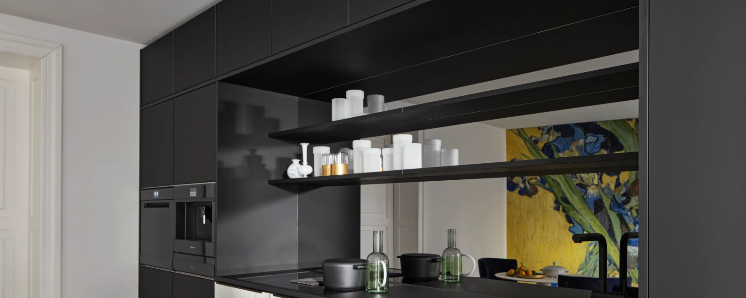 Eine moderne, schwarze Küche mit Regalen und Geräten, gestaltet von Nolte Küchen.