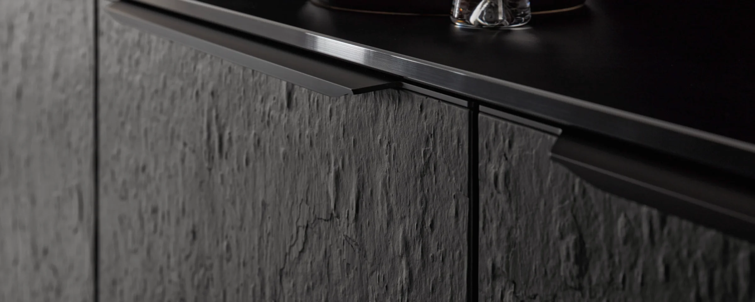 Una cocina moderna con frentes oscuros y texturizados y detalles elegantes de Nolte Cocina.