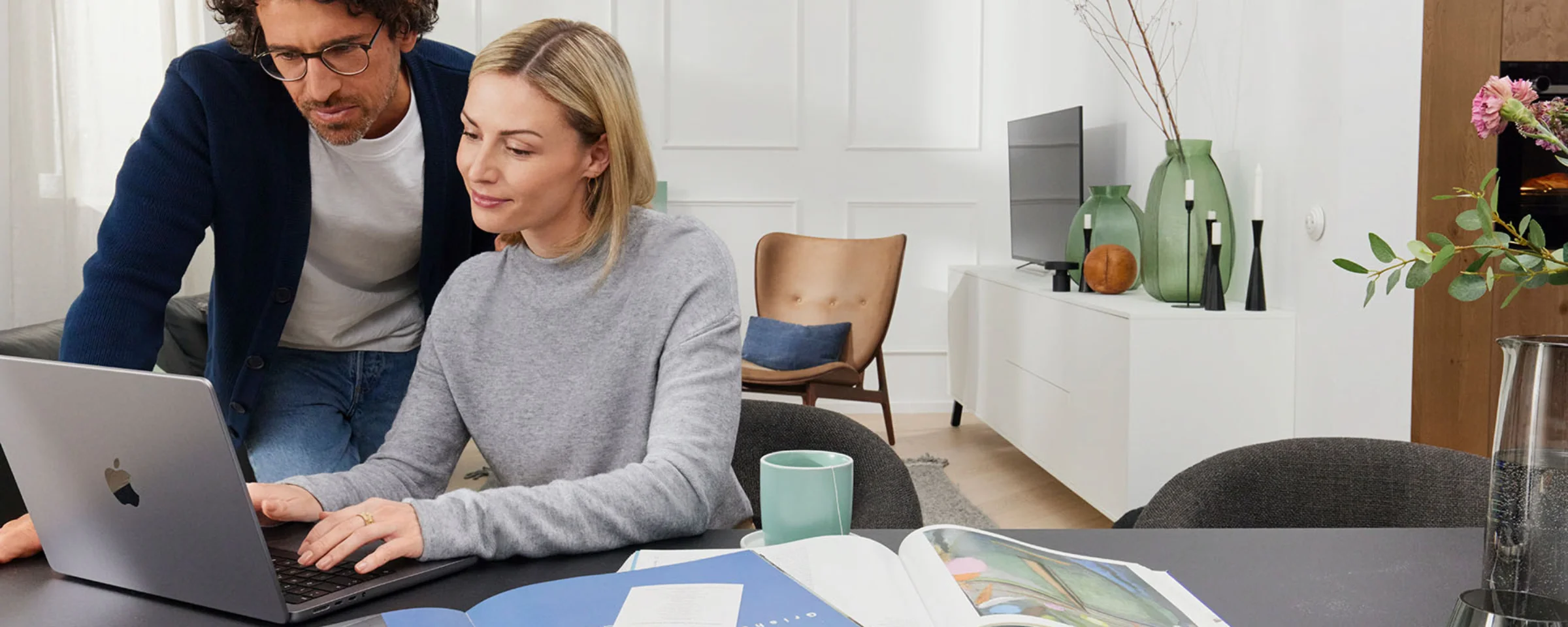 Ein Paar arbeitet gemeinsam an einem Laptop in einem modernen Wohnzimmer mit Nolte Living.