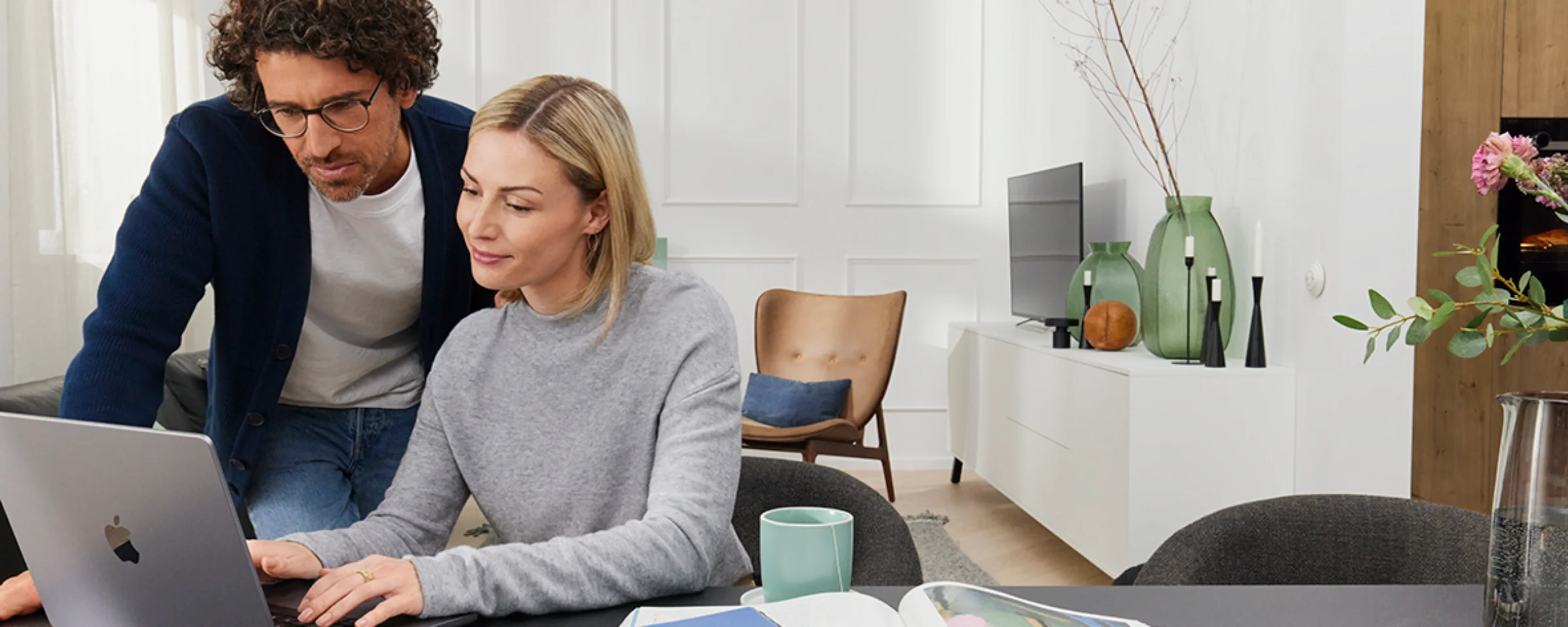 Ein Paar arbeitet an einem Laptop in einem modern eingerichteten Wohnzimmer. Nolte Living.