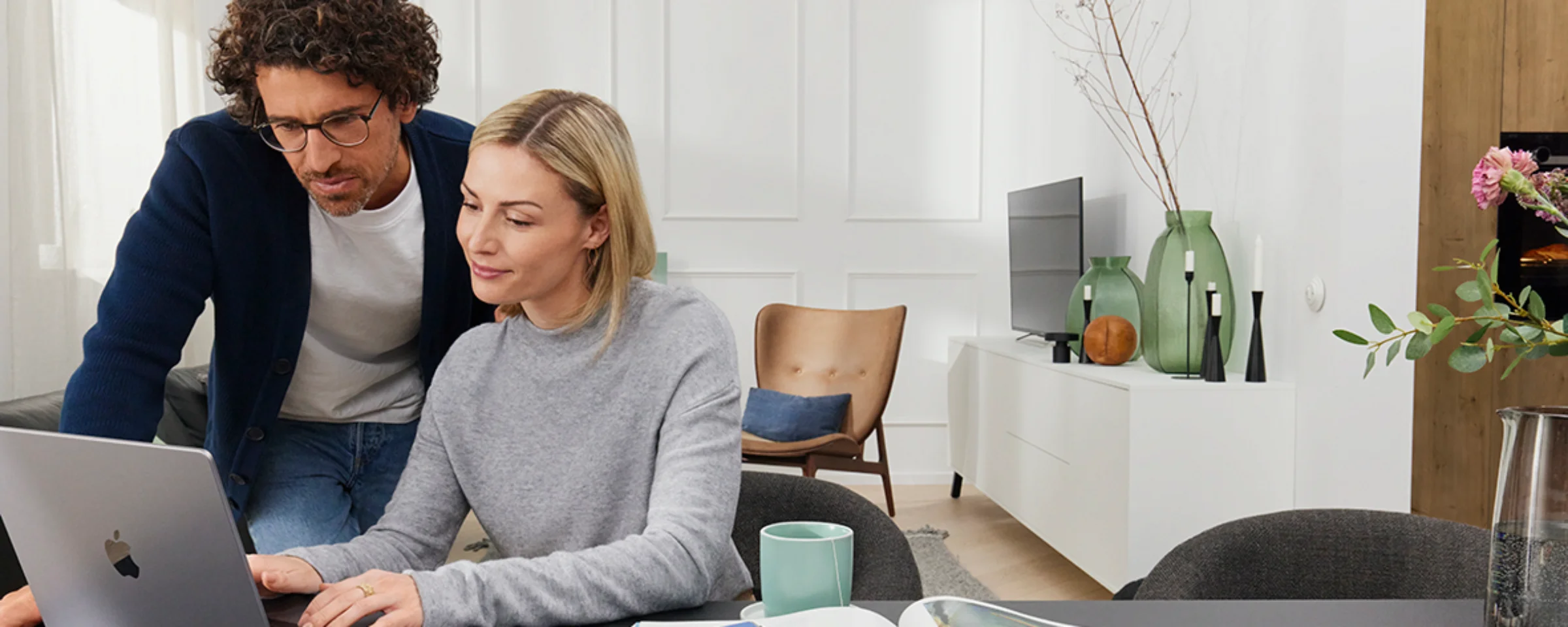 Ein Paar arbeitet an einem Laptop in einem modernen Wohnzimmer mit Nolte Living.