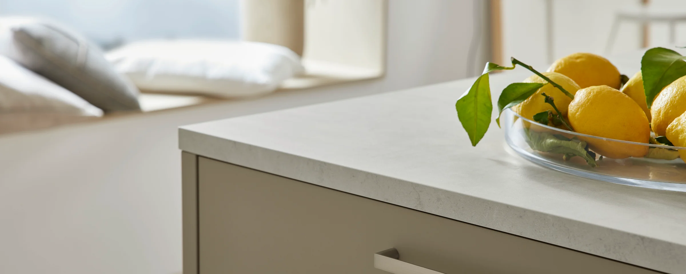 Eine moderne Küche mit Zitronen auf der Arbeitsplatte und einem Fensterplatz im Hintergrund bietet Nolte Küchen.