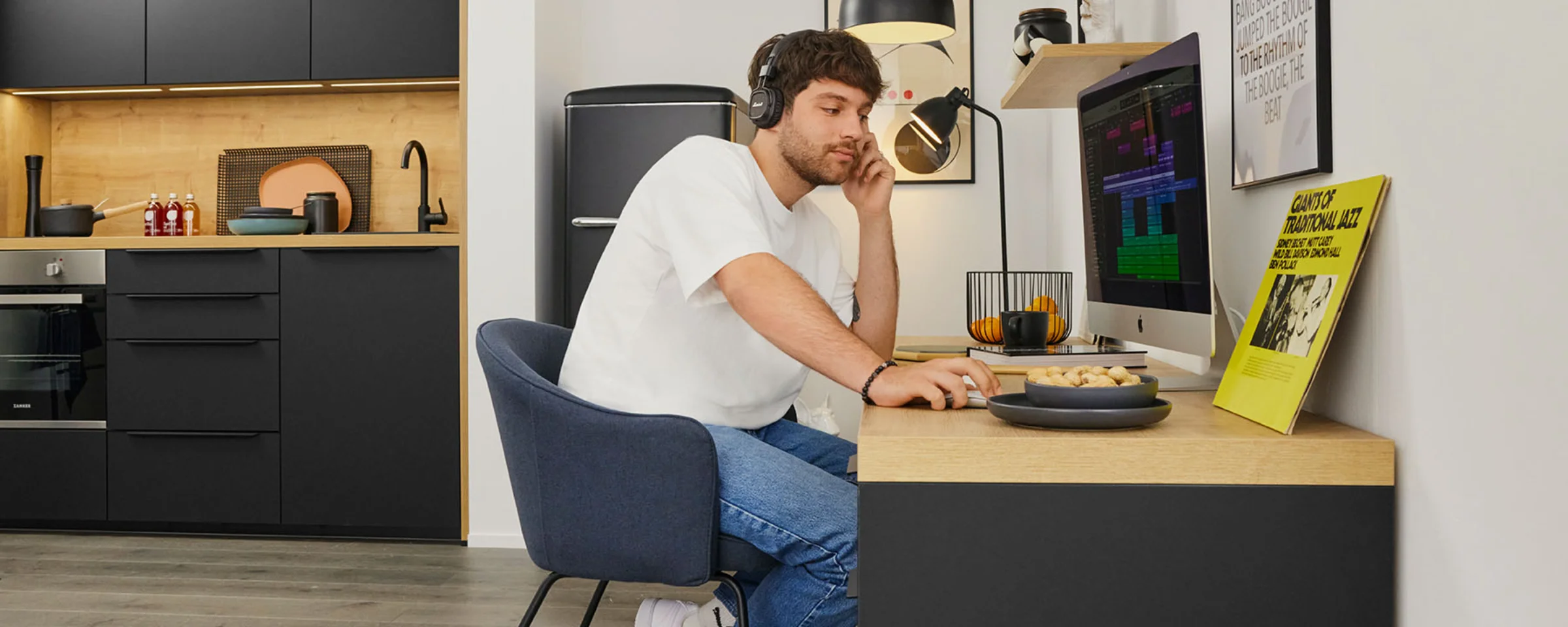 Un uomo lavora in una cucina moderna di Nolte Kitchen, seduto alla scrivania con un computer.