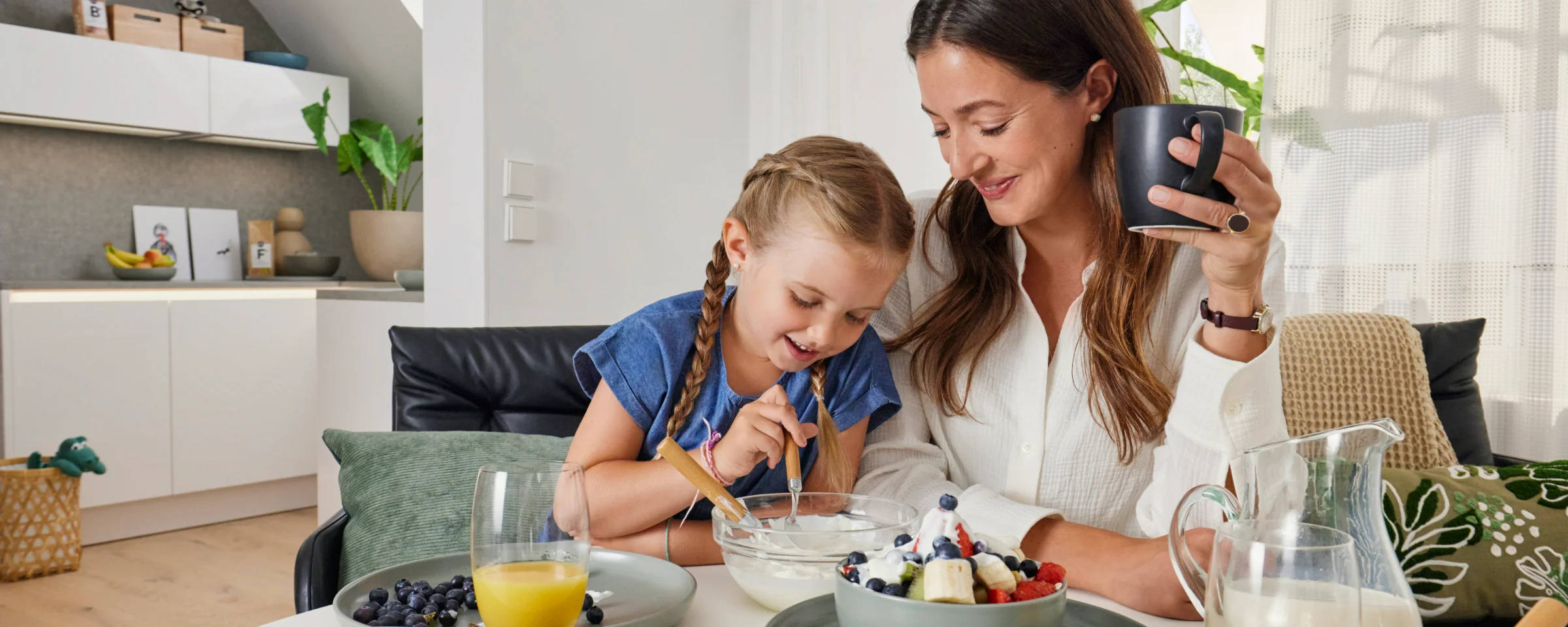 Eine Mutter und Tochter frühstücken gemeinsam in einer modernen Küche von Nolte Küchen.