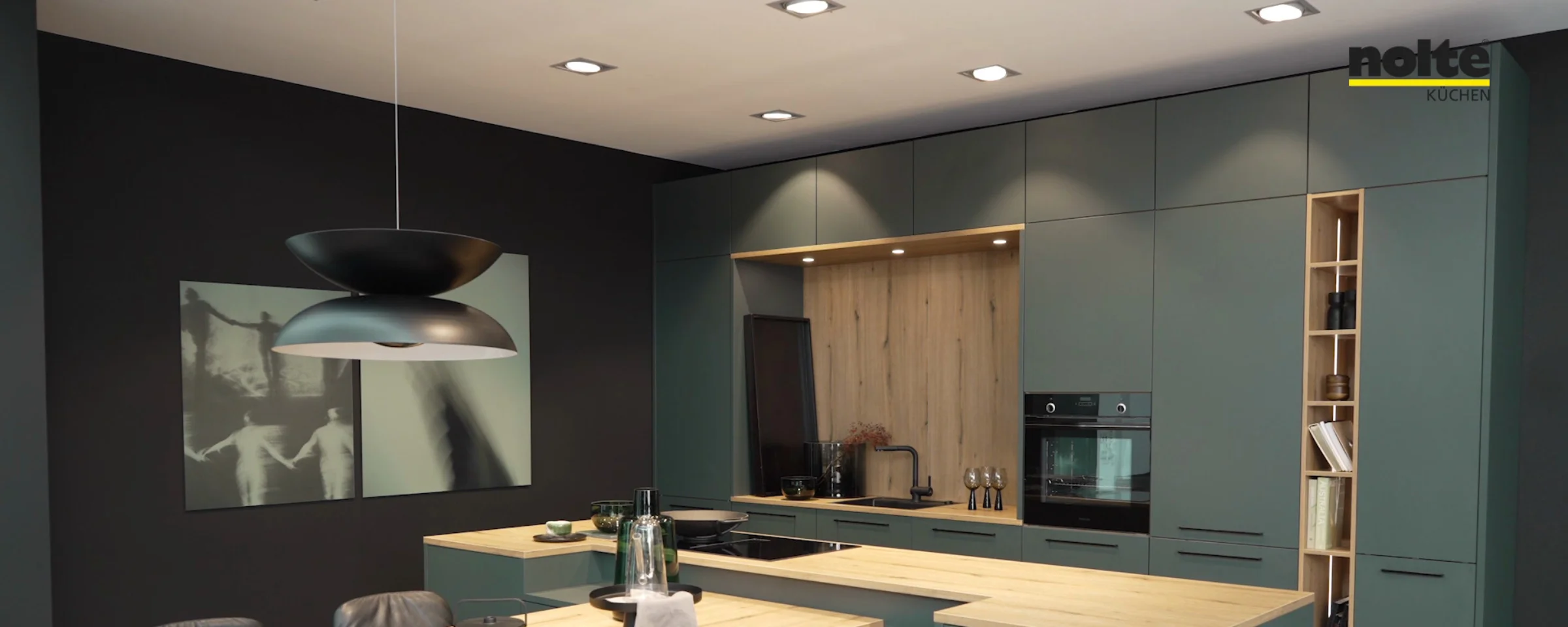 Eine moderne Küche mit grünen Schränken und Holzarbeitsplatten, eingerichtet von Nolte Küchen.