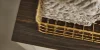 Ein goldener Korb mit Handtüchern steht auf einem dunklen Holzregal von Nolte Living.