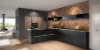 Cuisine Nolte moderne avec les façades FLAIR en noir avec un aspect laiton et FERRO en acier Corten. La combinaison entre l’élégance sombre et la surface à l’aspect industriel confère à la cuisine un caractère luxueux et urbain. Les lignes d’accent couleur laiton soulignent le design sans poignées et créent des touches stylées devant le mur aux tons chauds avec un aspect rouille.