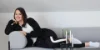 Eine Frau entspannt auf einem grauen Sofa, das Teil der Nolte Living Kollektion ist.