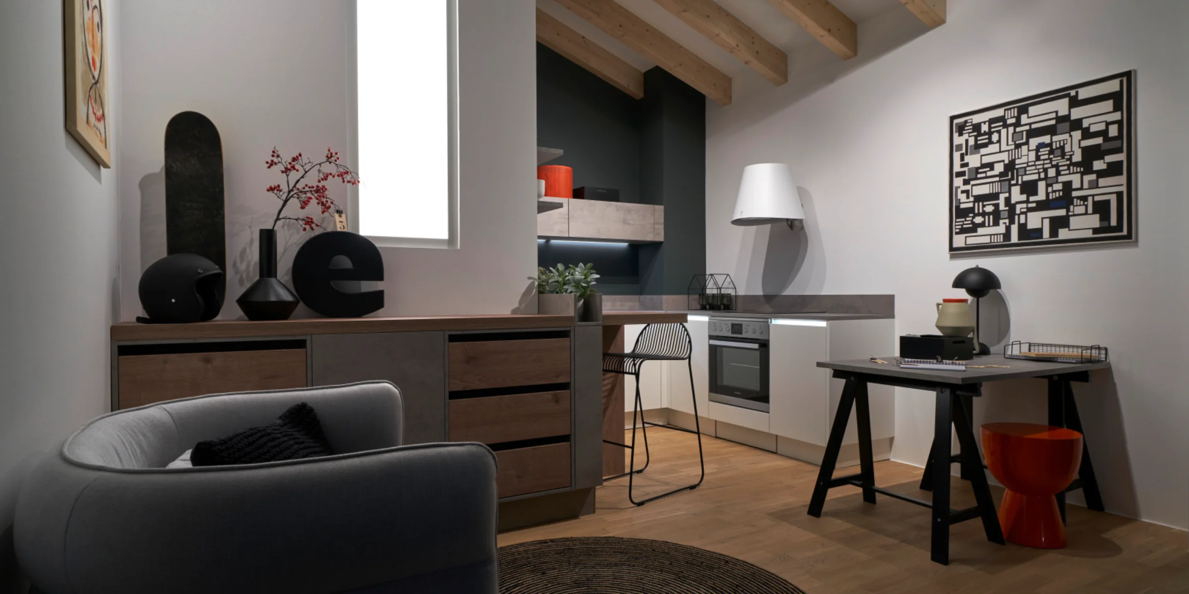 Cuisine tiny aménagée avec style sous des combles, avec le programme de façades FEEL en blanc mat et un plan de travail STONE aspect béton en contraste. Planification compacte avec espace de vie et de travail dans une seule pièce.