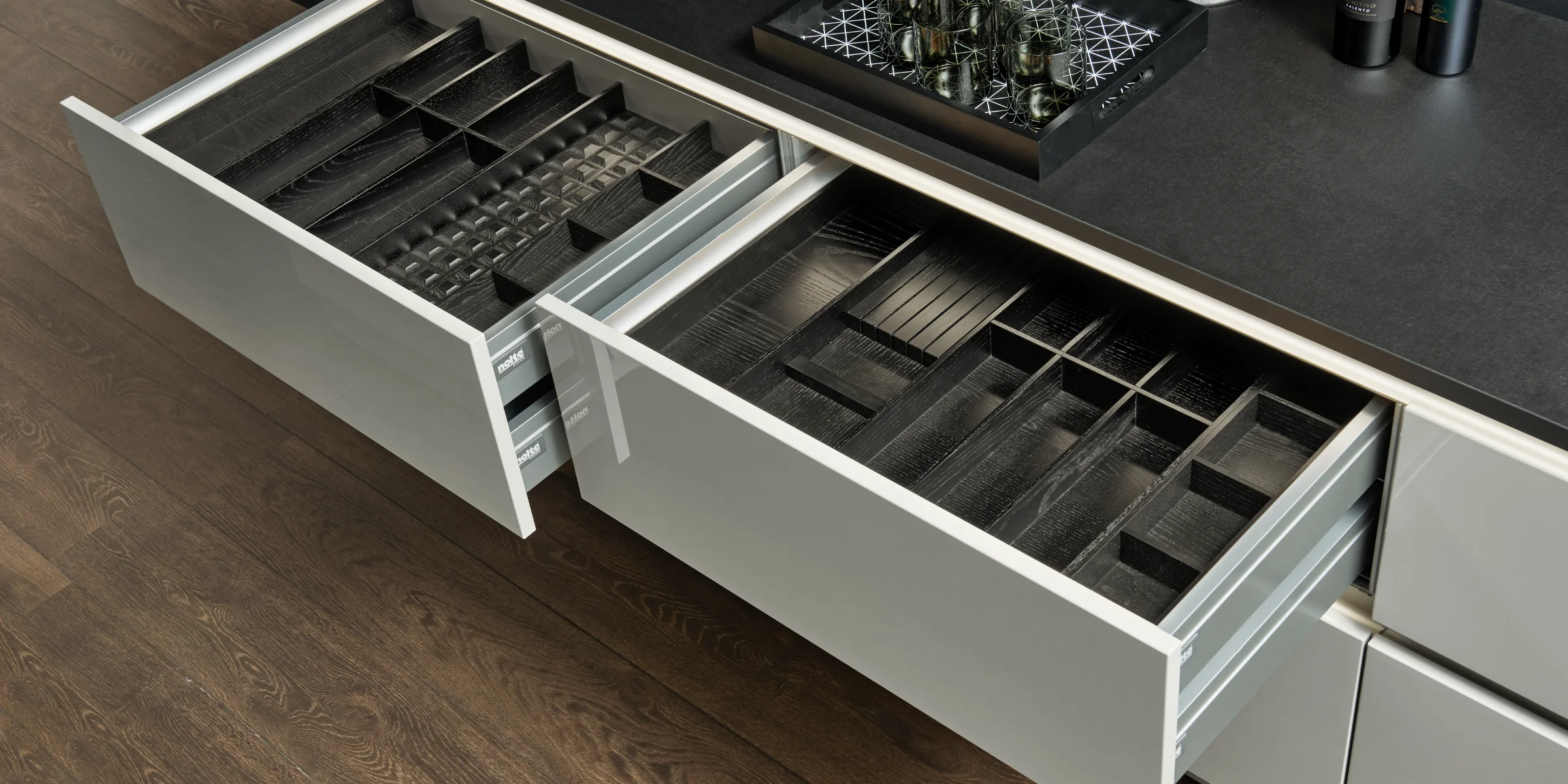 Offene Schubladen einer modernen Küche mit Besteckeinsätzen, präsentiert von Nolte Küchen.