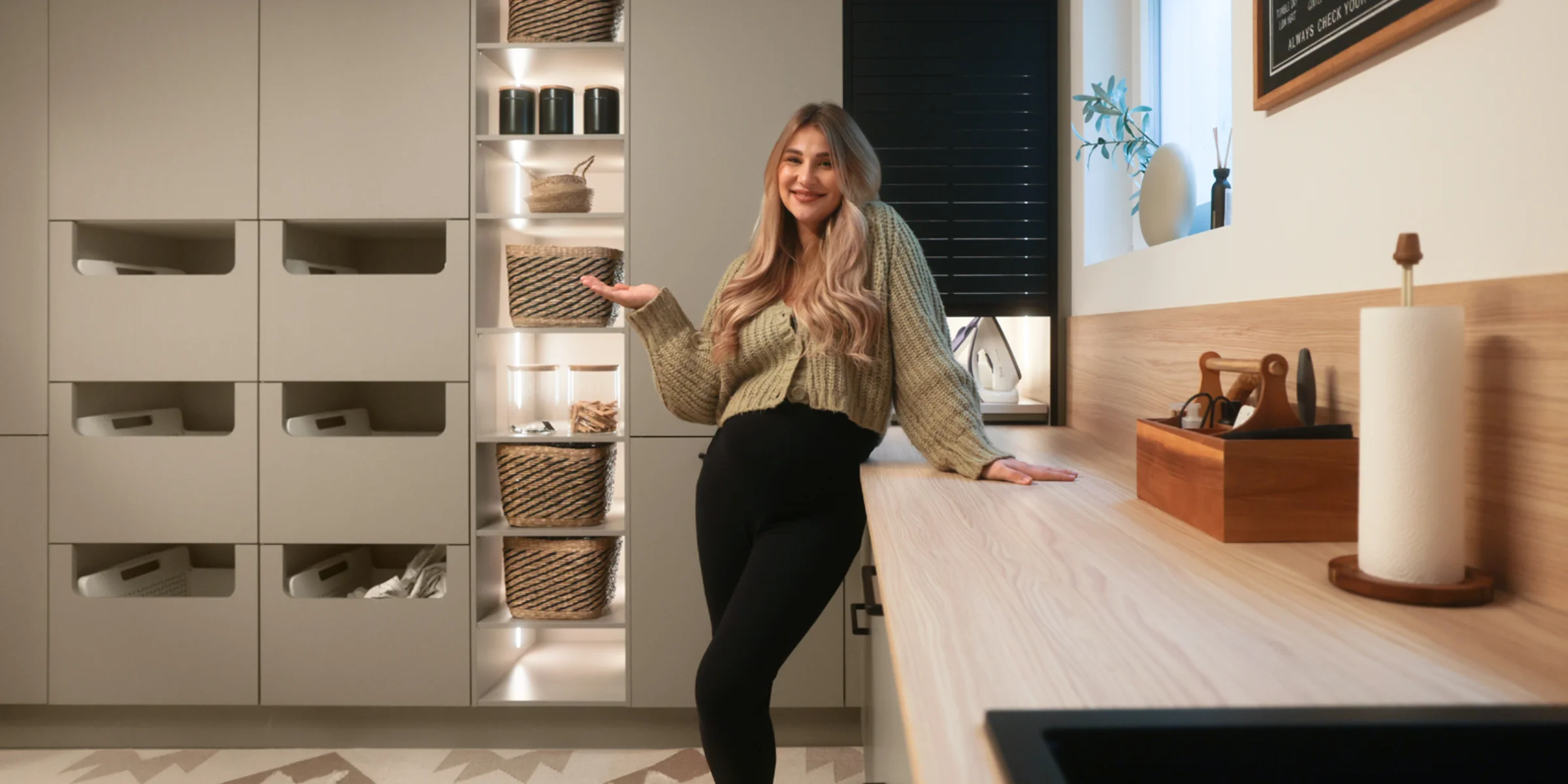 Eine Frau steht lächelnd in einem modernen Hauswirtschaftsraum von Nolte Hauswirtschaftsräume.