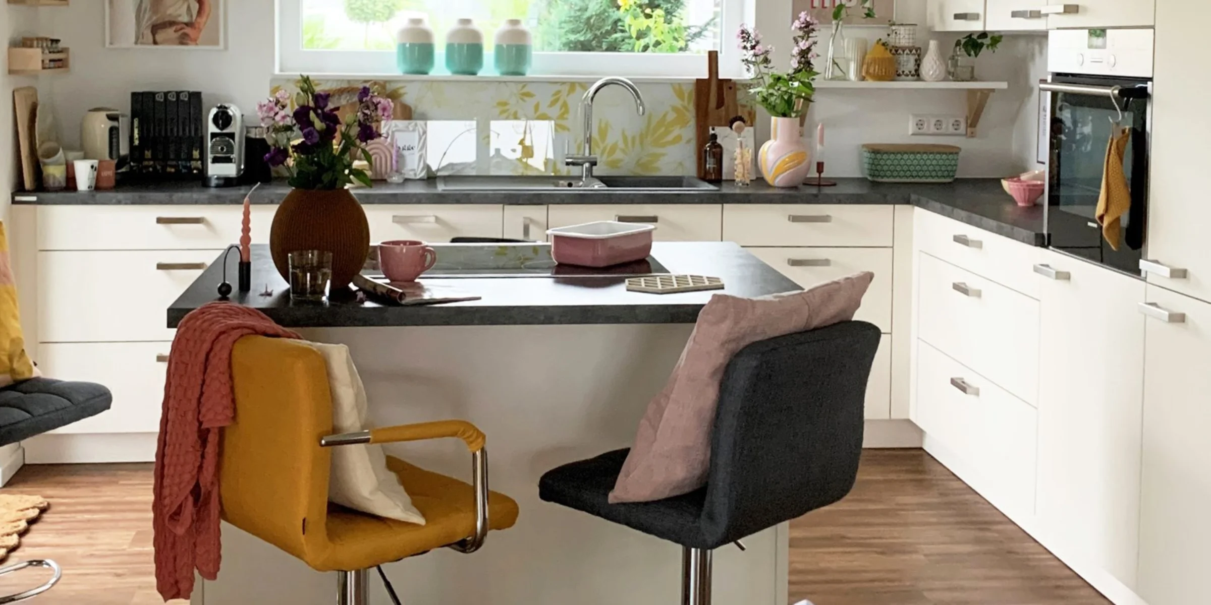 Eine moderne, helle Küche mit Insel und farbigen Akzenten von Nolte Küchen.