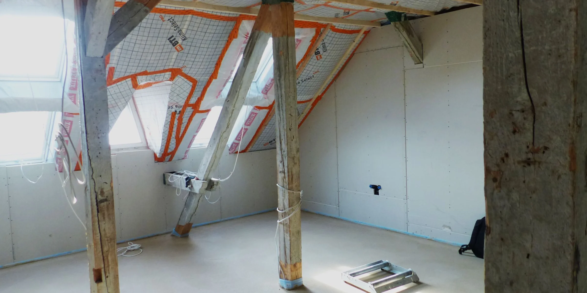 Ein unausgebauter Dachboden mit sichtbaren Holzstützen und Isolierung.