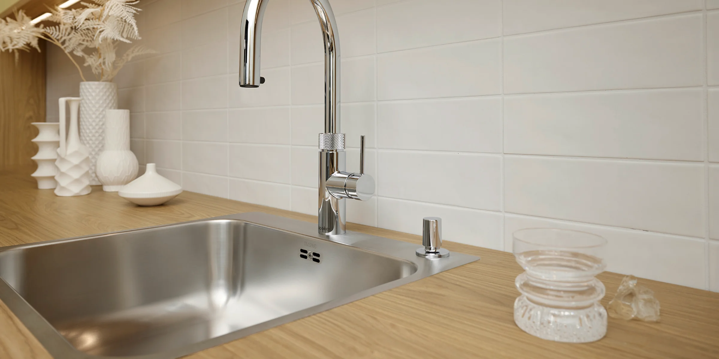 Eine moderne Küche mit Holzarbeitsplatte und Edelstahlspüle von Nolte Küchen.