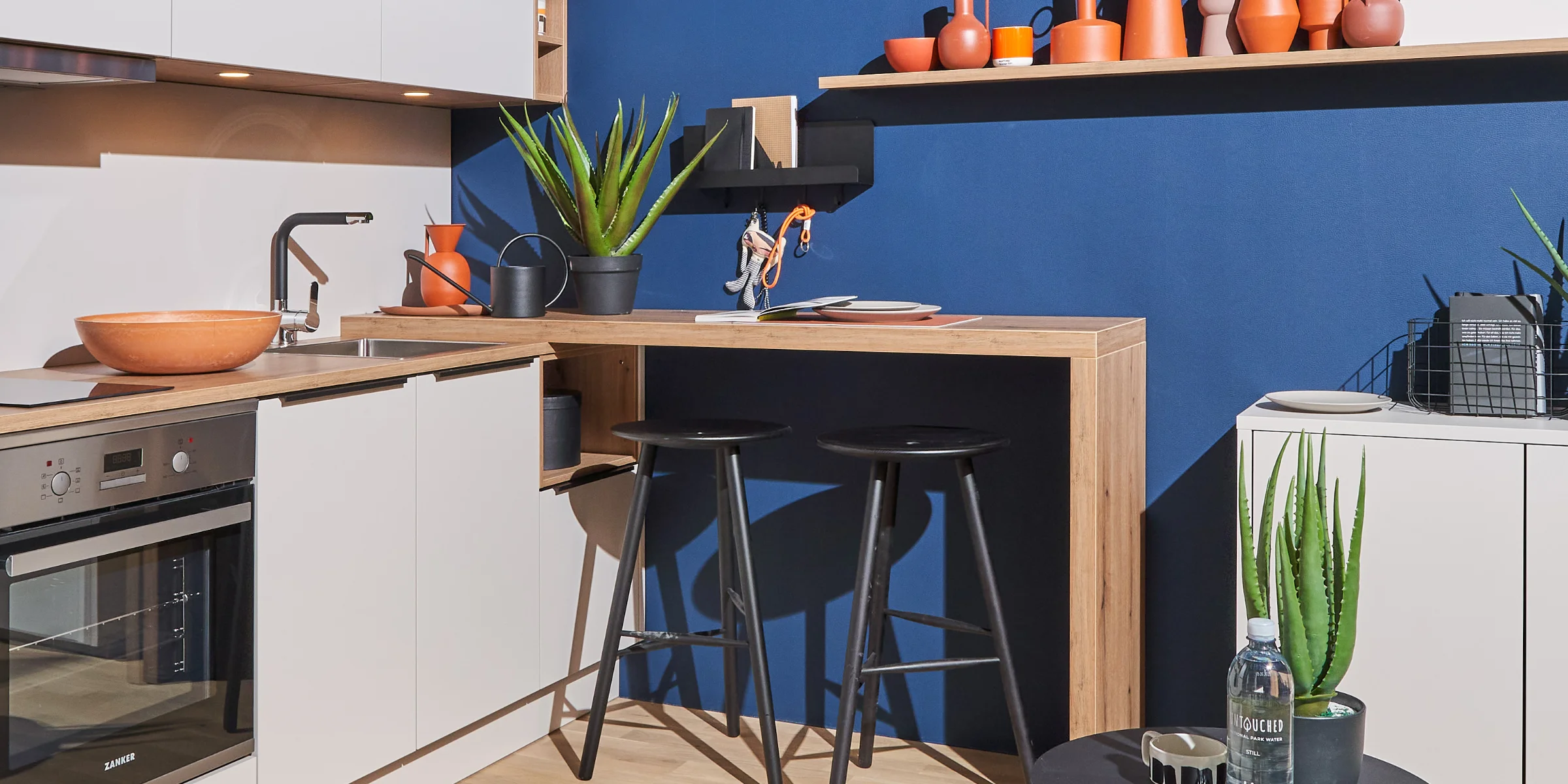 Eine moderne Küche mit blauen Wänden und Pflanzen, gestaltet von Nolte Küchen.