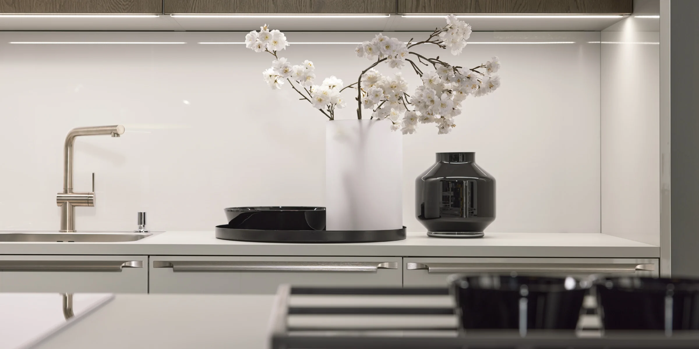 Eine moderne Küche mit weißen Schränken und Blumen in einer Vase auf der Theke, gestaltet von Nolte Küchen.