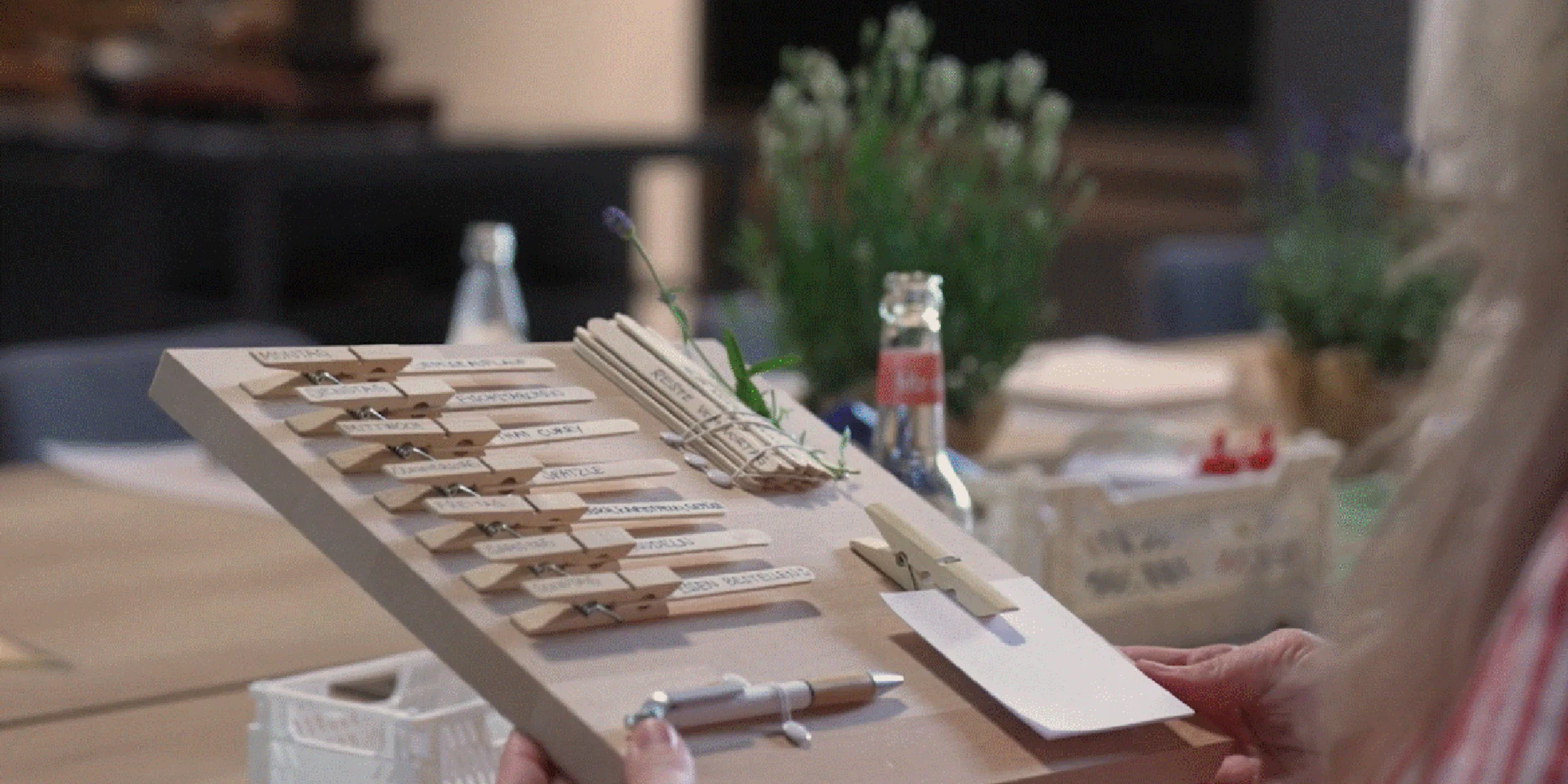 Eine Person hält Bastelmaterialien auf einem Tisch in einer modernen Küche von Nolte Küchen.