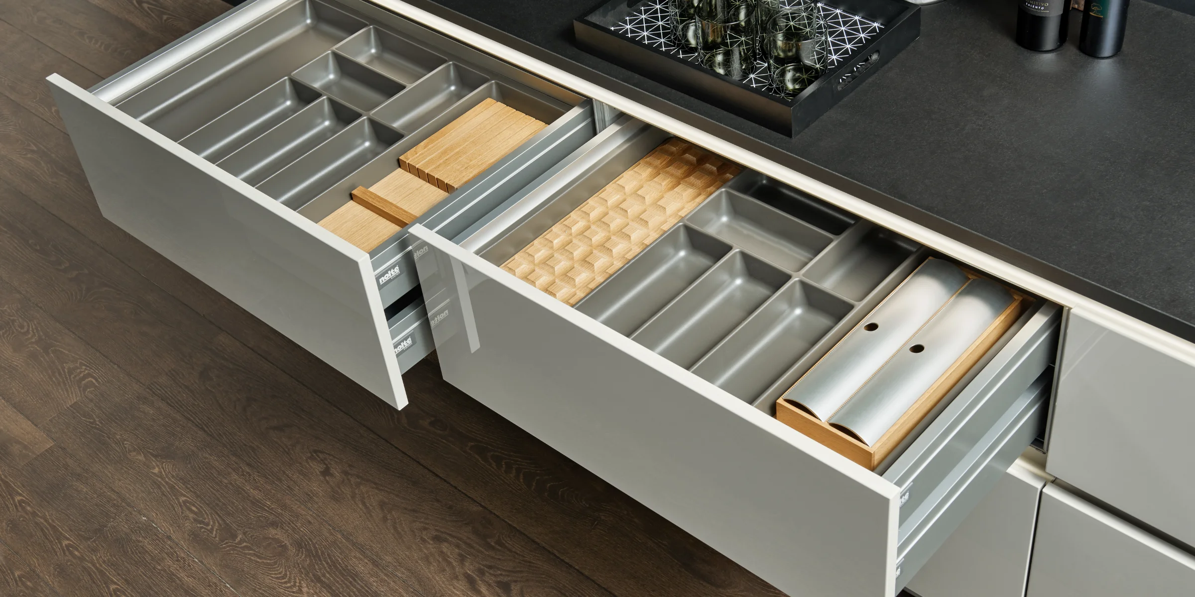 Geöffnete Küchenschubladen mit Besteckfächern und Schneidebrettern in einer modernen Küche von Nolte Küchen.