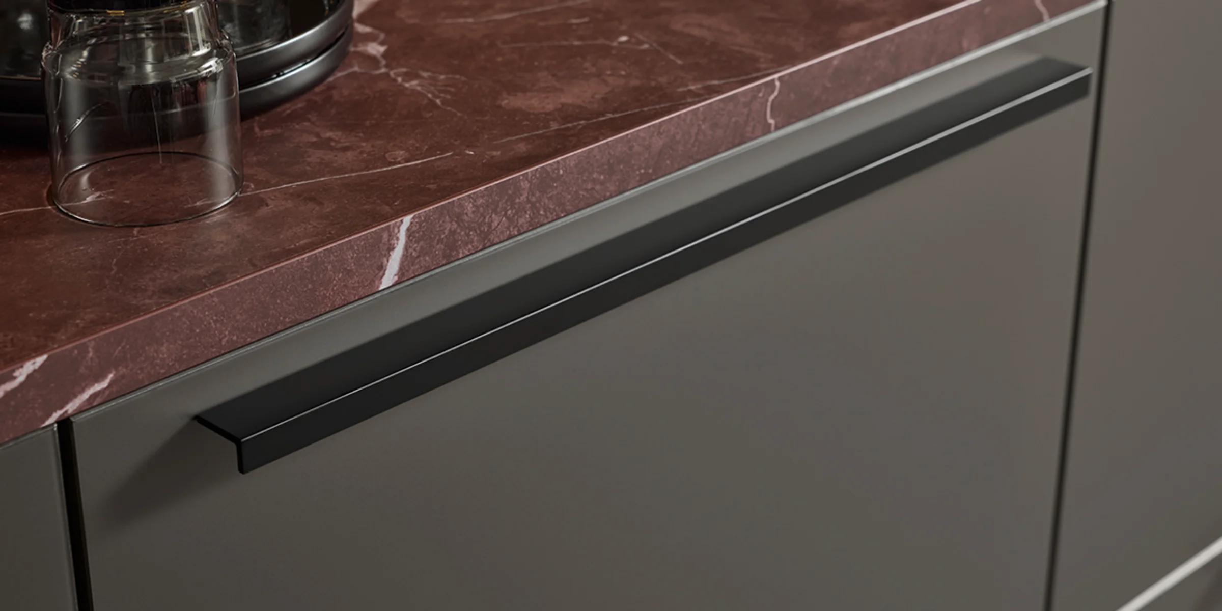 A sleek countertop with glasses and modern cabinets. Nolte Kitchens.