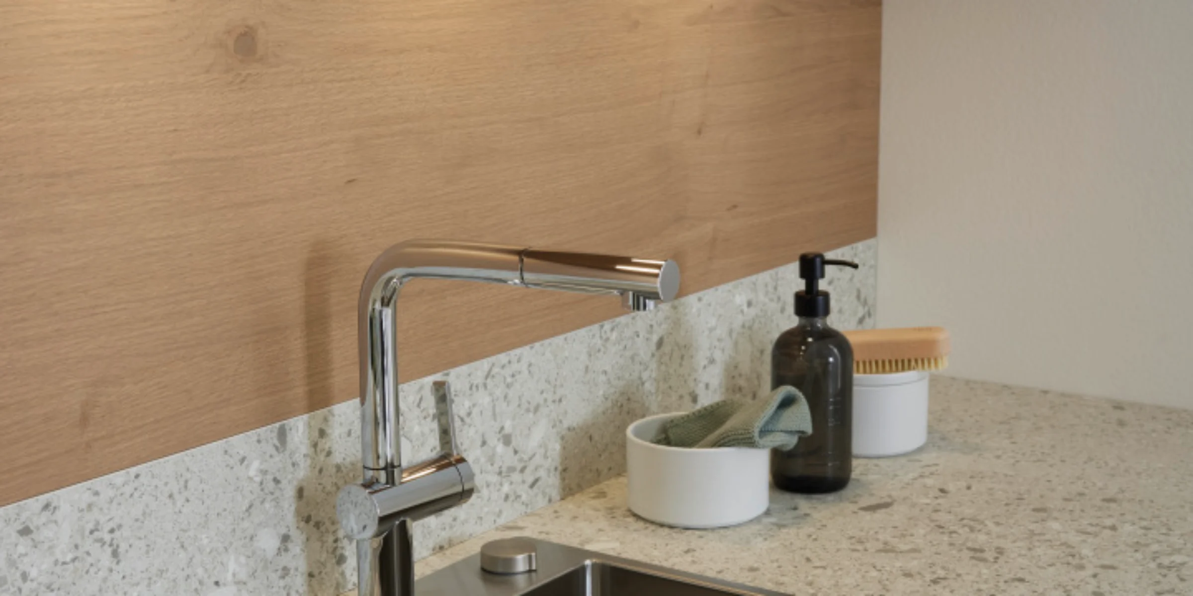 Eine moderne Küchenspüle mit Armatur und Ablagefläche, umgeben von Holz und Stein. Nolte Küchen.