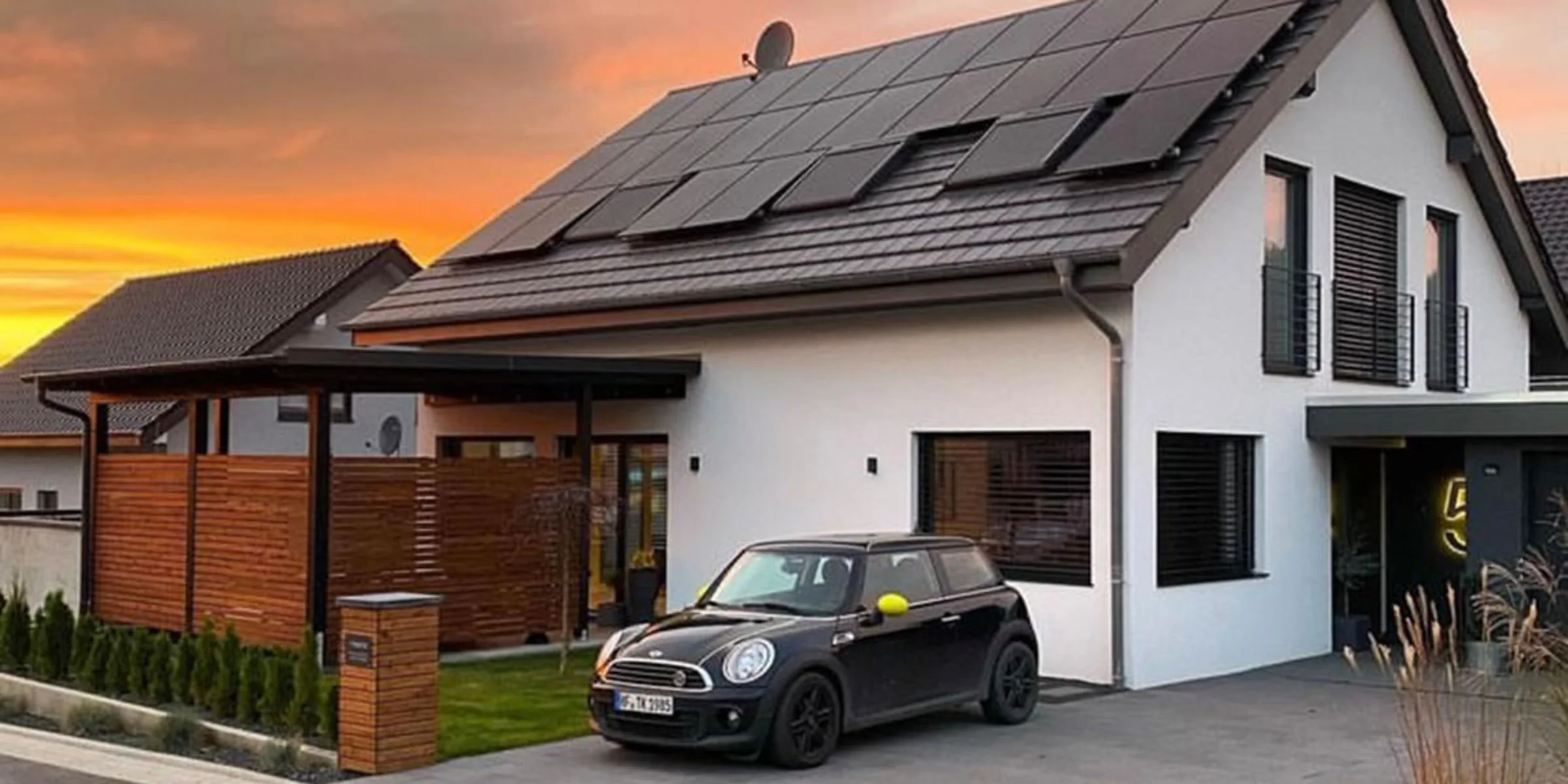 Ein modernes Einfamilienhaus mit Solarpanelen auf dem Dach bei Sonnenuntergang.