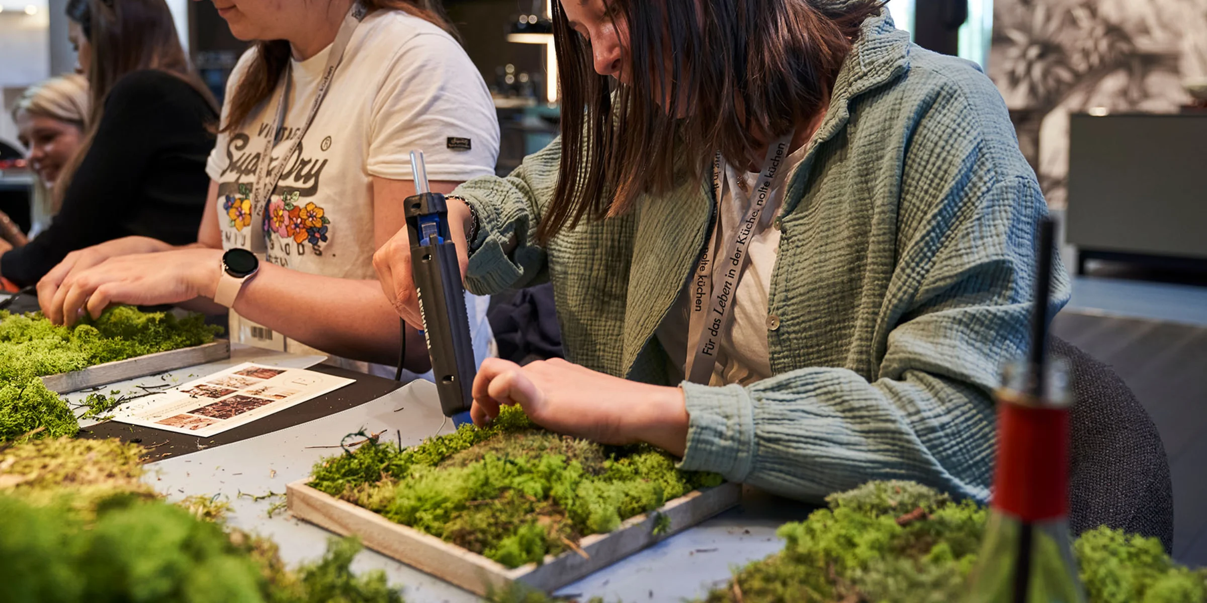 Deux femmes travaillent à une table avec de la mousse dans une pièce moderne.