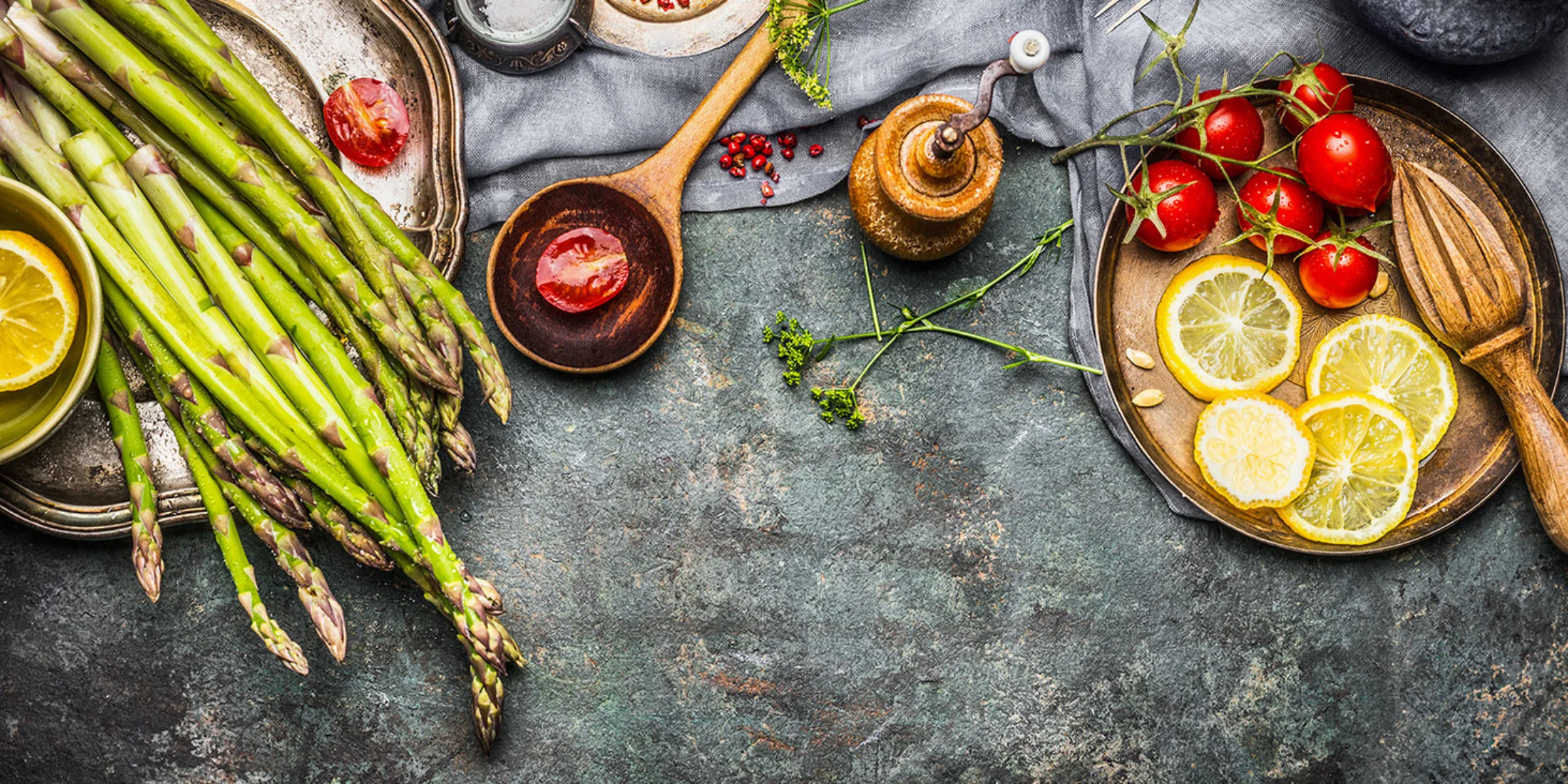 Frischer Spargel und Tomaten mit Gewürzen und Zitronenscheiben auf rustikalem Untergrund, inspiriert von NolteNeo.