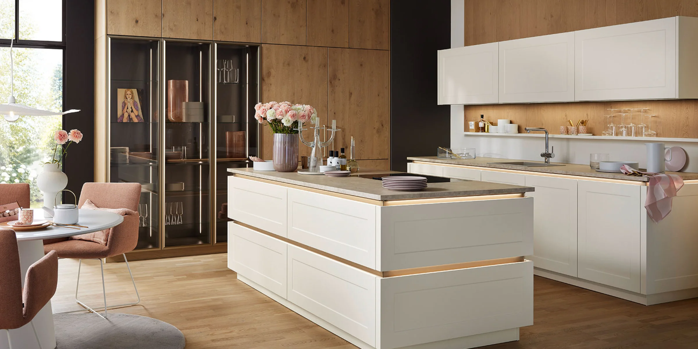 Una cocina moderna con armarios blancos y detalles de madera de Nolte Cocina.