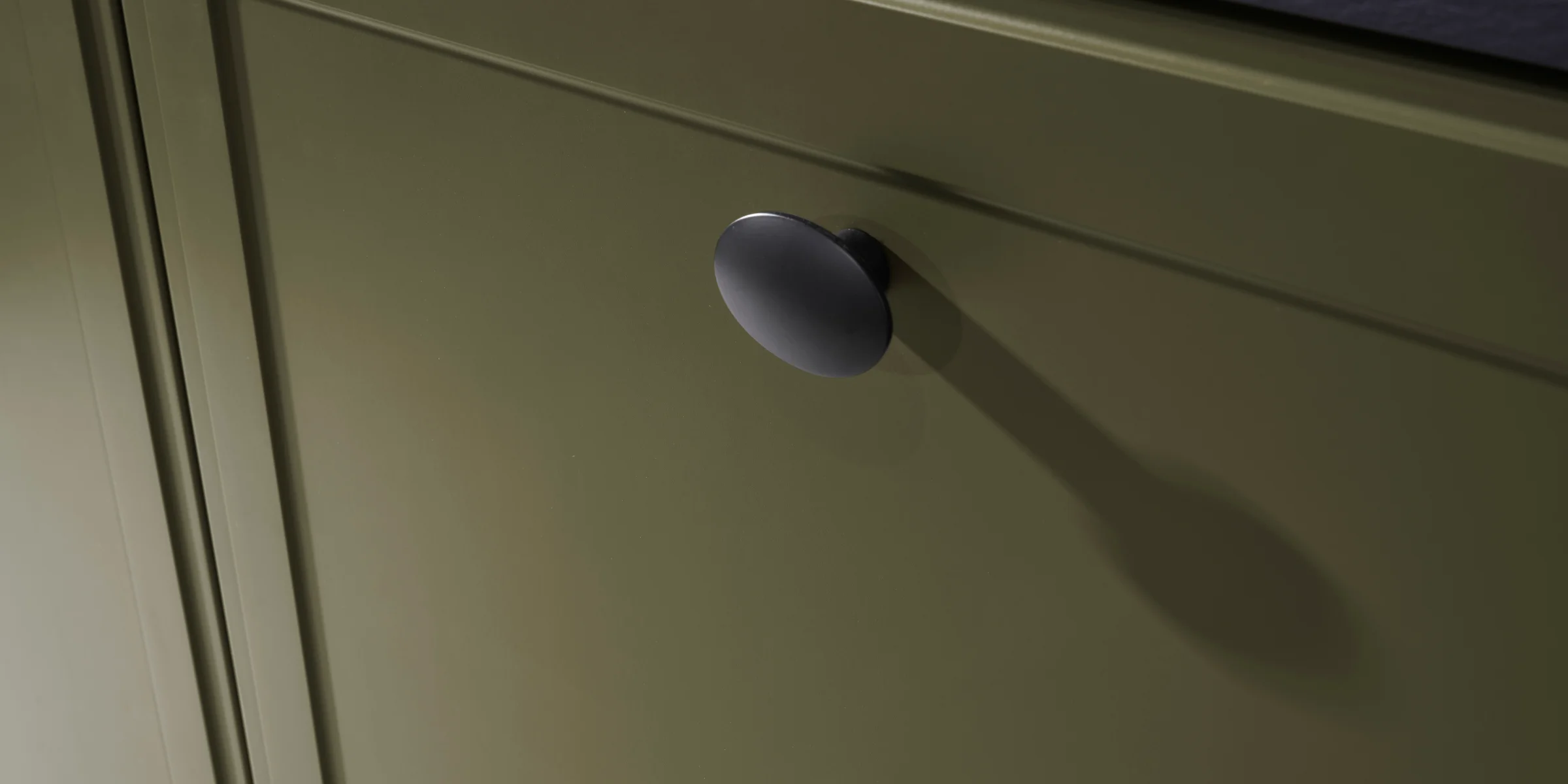 Ein grüner Küchenschrank mit schwarzem Griff, Teil von Nolte Küchen.