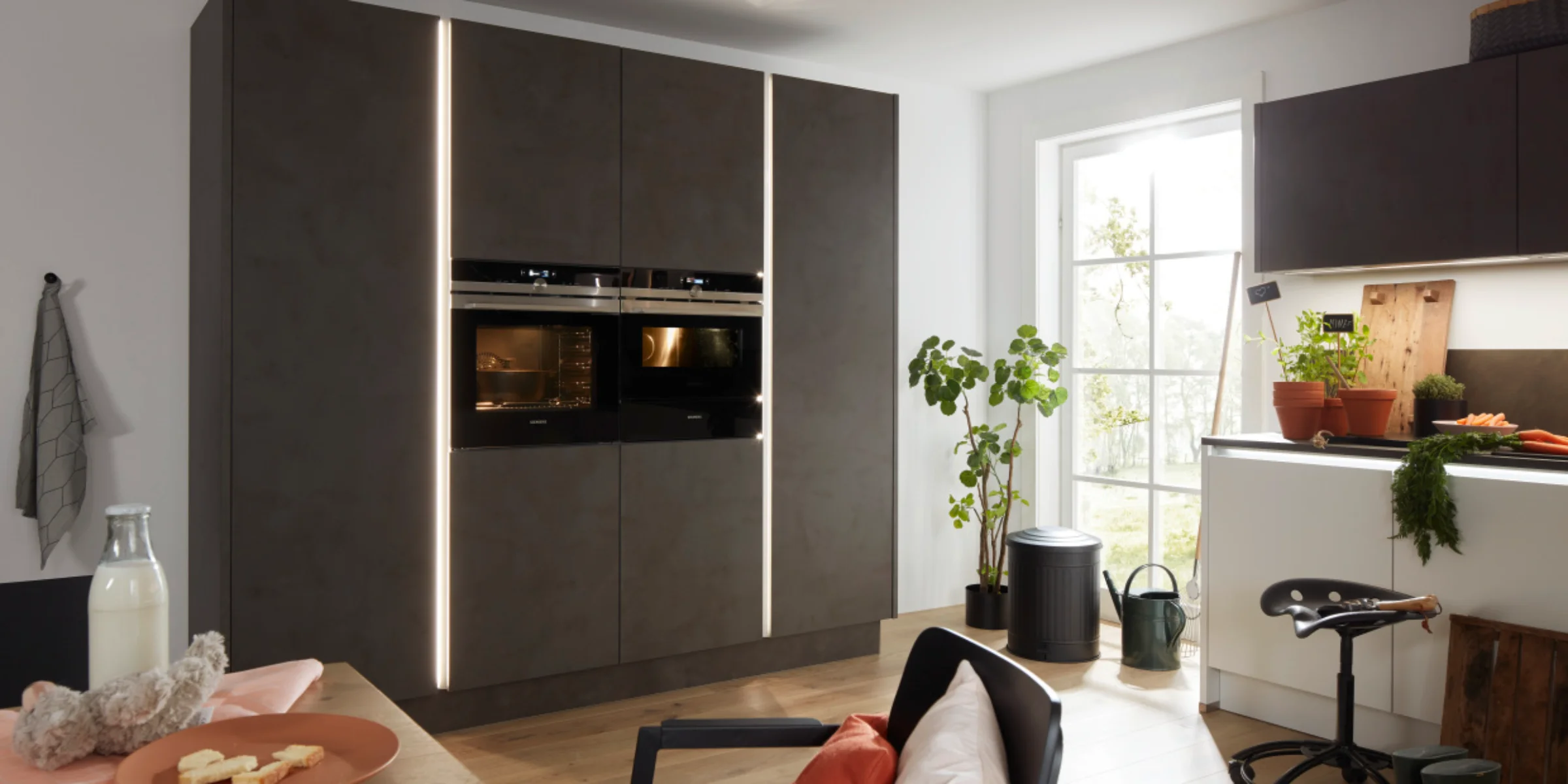 A modern kitchen with black cabinets and plenty of natural light by Nolte Kitchen.