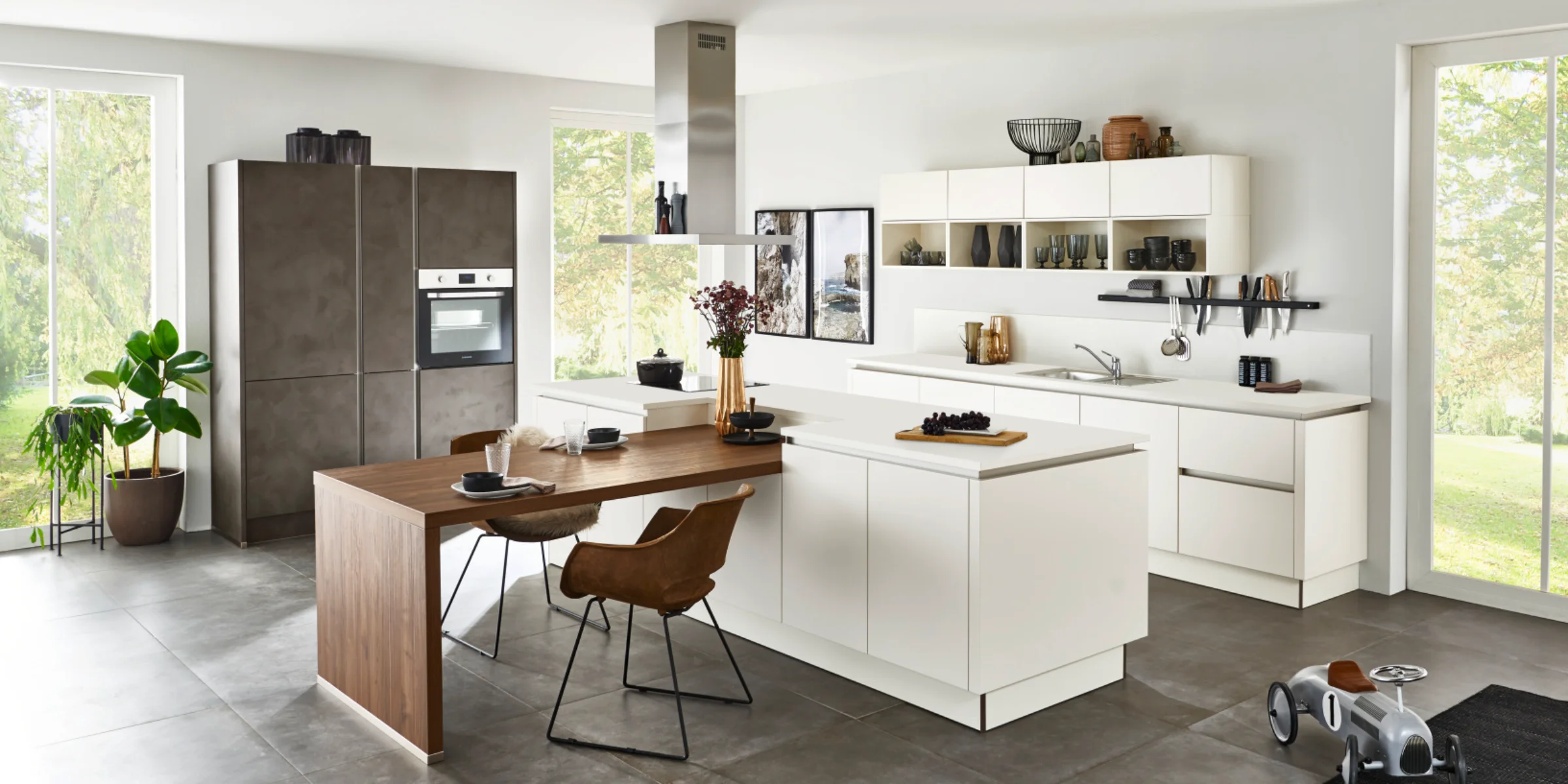 Moderne Nolte Küche mit Fronten in SOFT LACK Magnolia softmatt und PORTLAND Zement Anthrazit, kombiniert mit Holz-Esstisch und großzügigem Raumkonzept in heller Wohnatmosphäre.