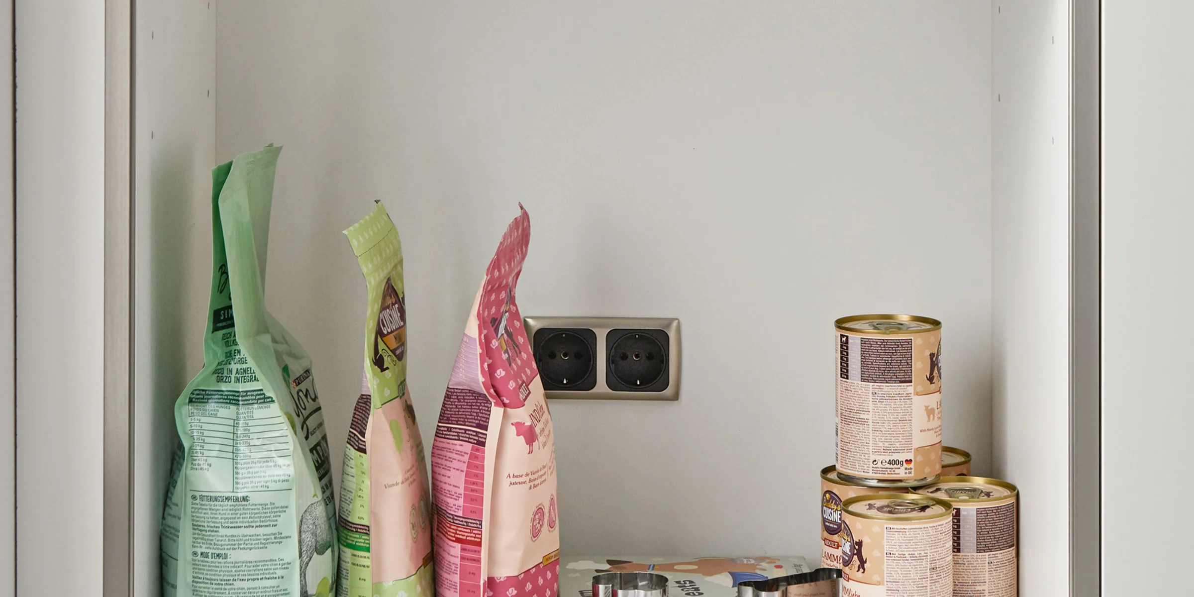 Ein Regal mit Tierfutter und Dosen in einem Hauswirtschaftsraum, Nolte Hauswirtschaftsräume.