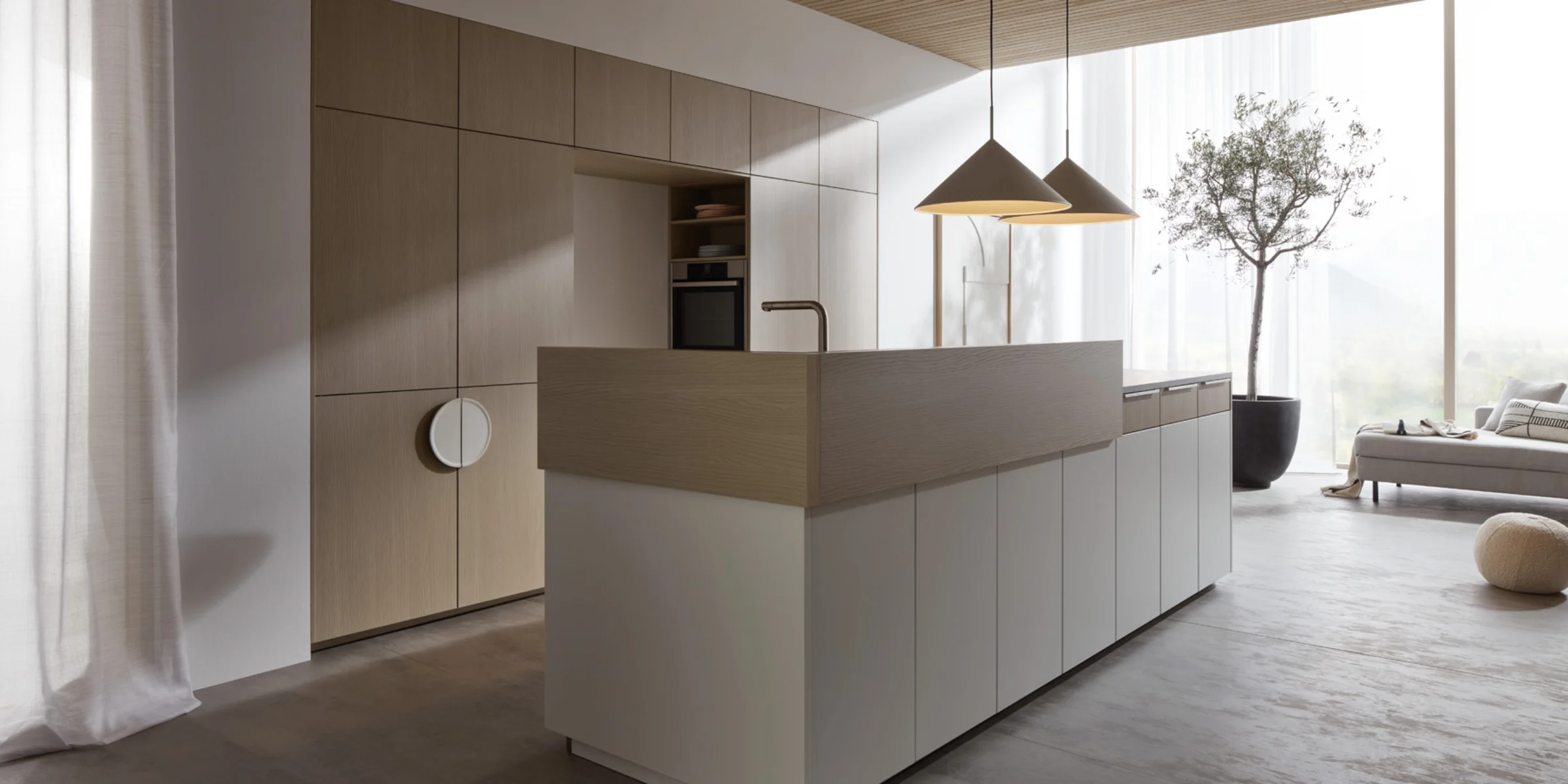 Eine moderne Küche mit Insel und Holzdetails, beleuchtet von Hängeleuchten. Nolte Küchen.