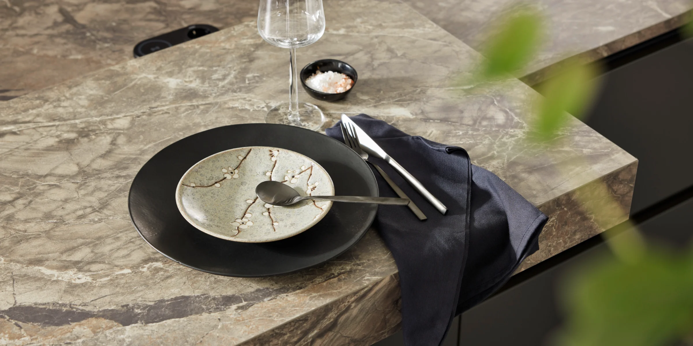 Ein stilvoll gedeckter Tisch mit modernem Geschirr auf einer Küchenarbeitsplatte von Nolte Küchen.