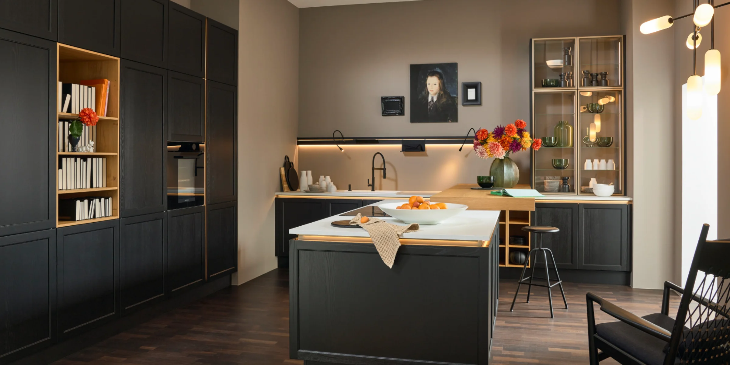 Eine moderne Küche mit dunklen Schränken und zentraler Kochinsel von Nolte Küchen.