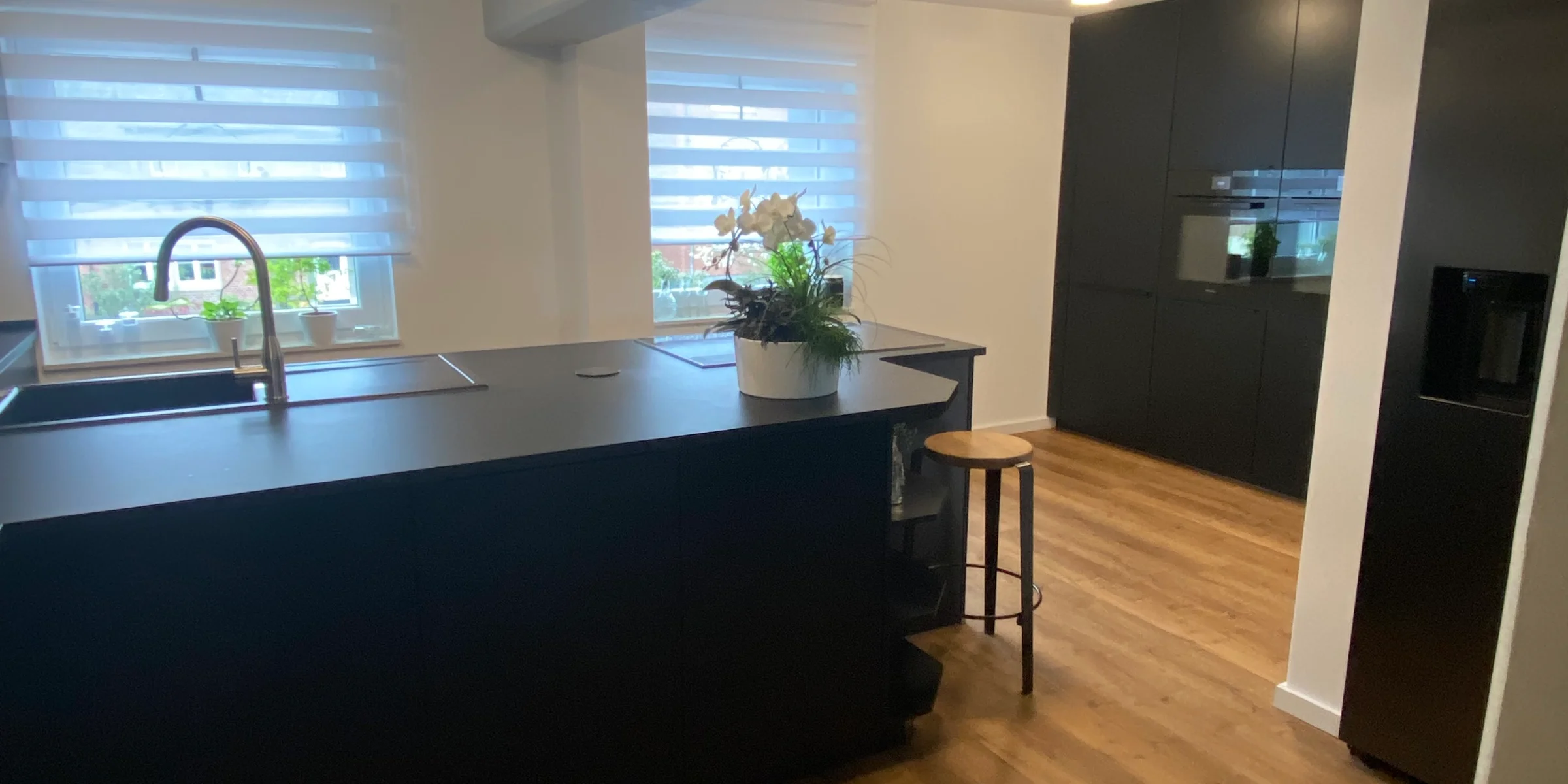 Eine moderne Küche mit dunklen Schränken und Holzfußboden, ausgestattet von Nolte Küchen.