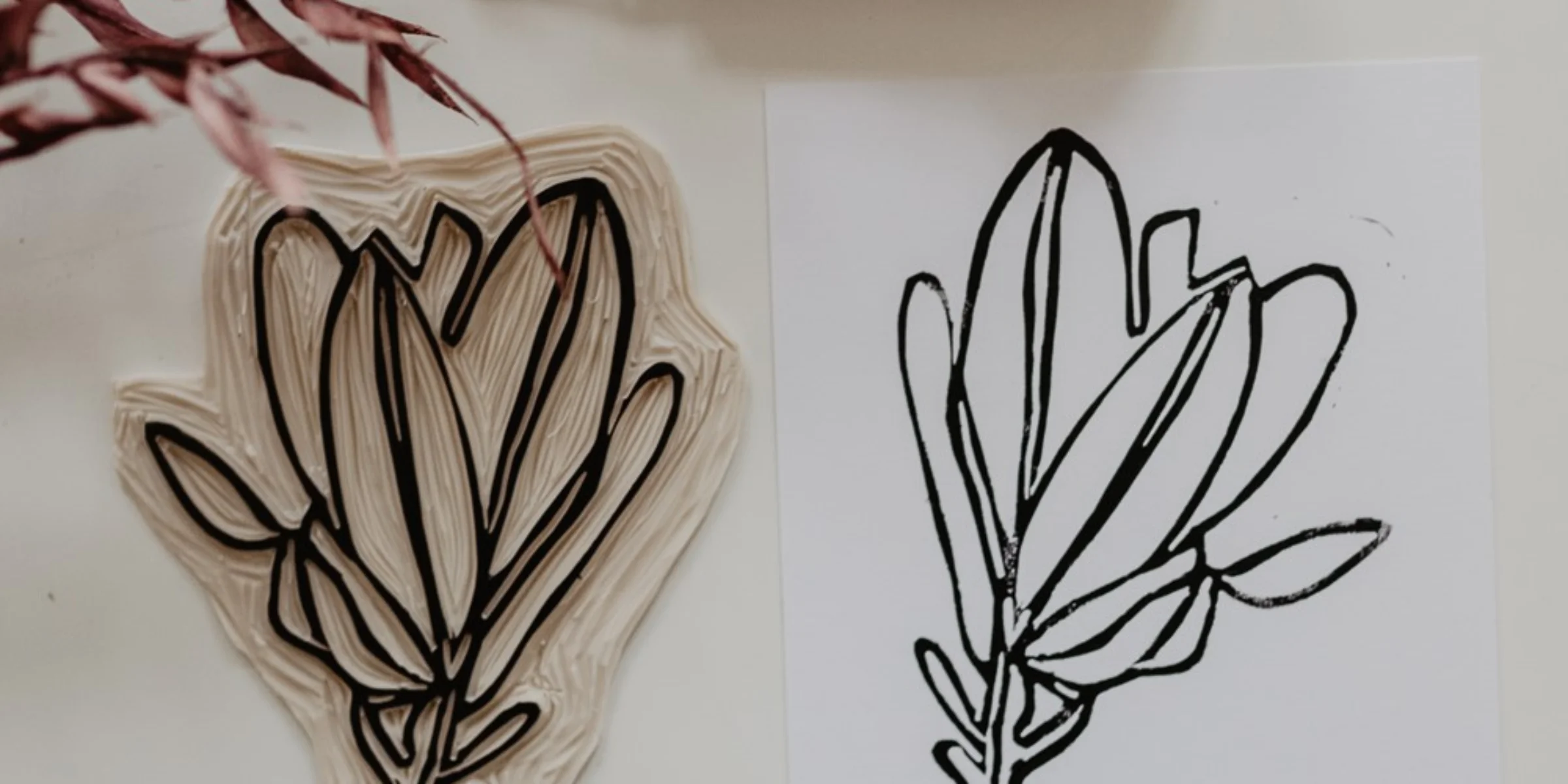 Ein geschnitzter Druckstempel mit Blattmotiv und die gedruckte Abbildung auf Papier.