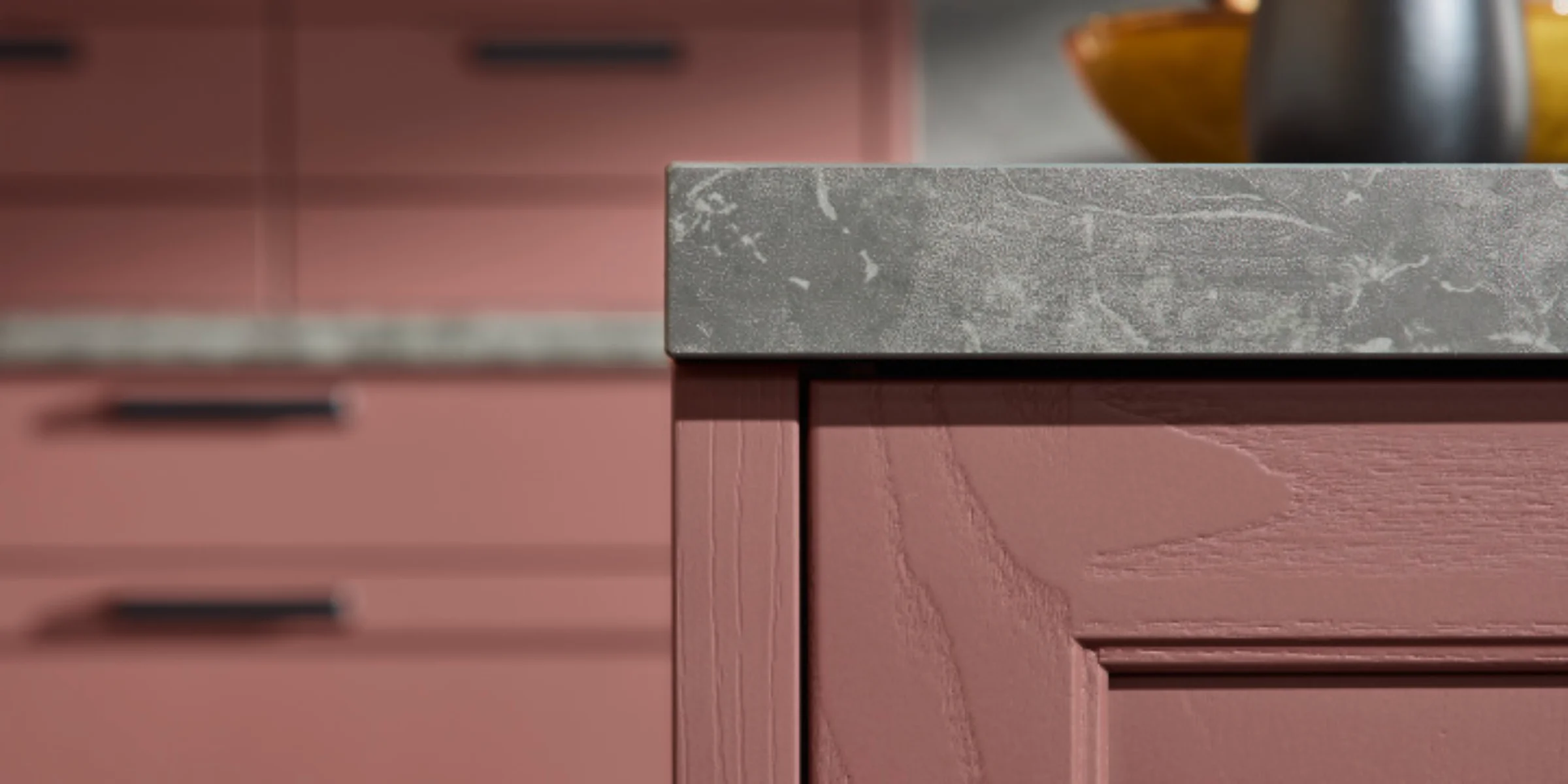 Eine stilvolle Küche mit rosa Schränken und grauer Arbeitsplatte, präsentiert von Nolte Küchen.