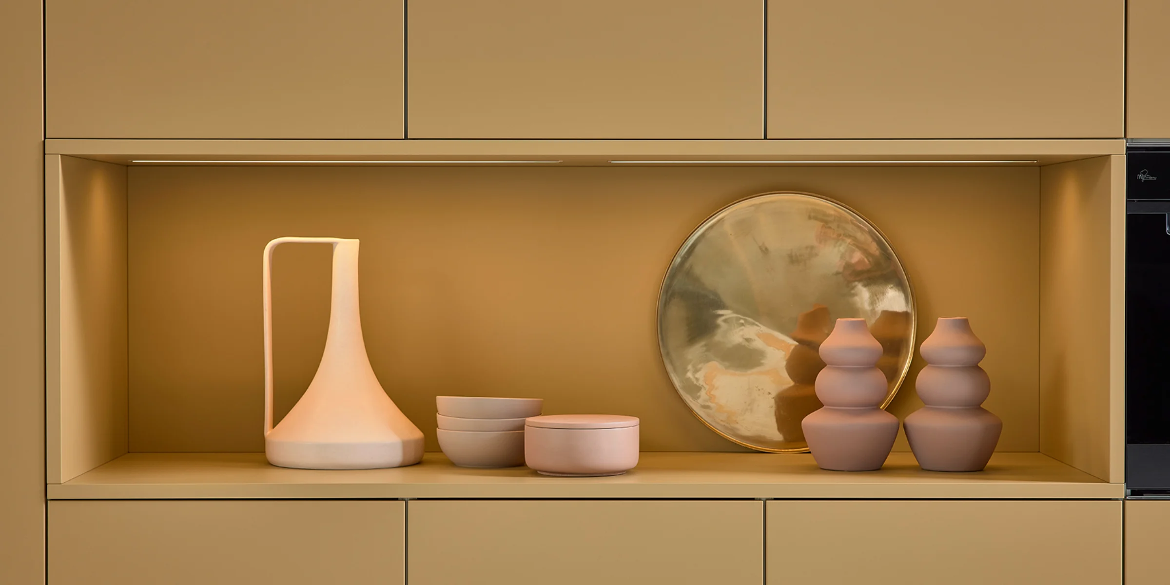 Ein Regal mit modernen Vasen und Schalen in einer eleganten Küche von Nolte Küchen.