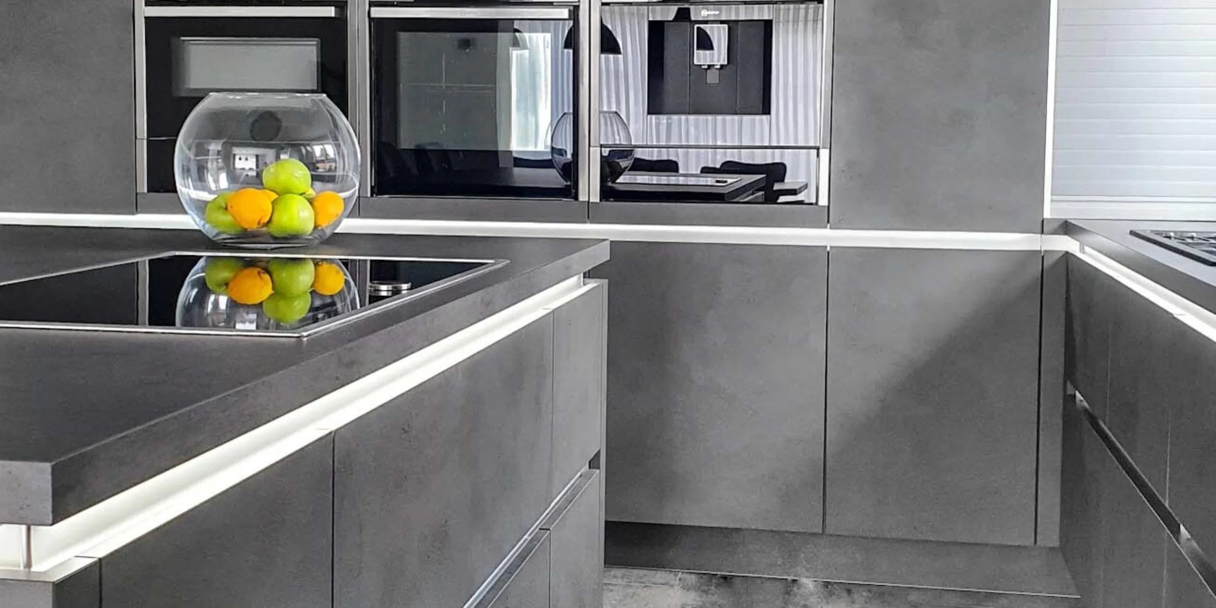 Eine moderne Küche mit grauen Schränken und einer Obstschale auf der Arbeitsplatte von Nolte Küchen.