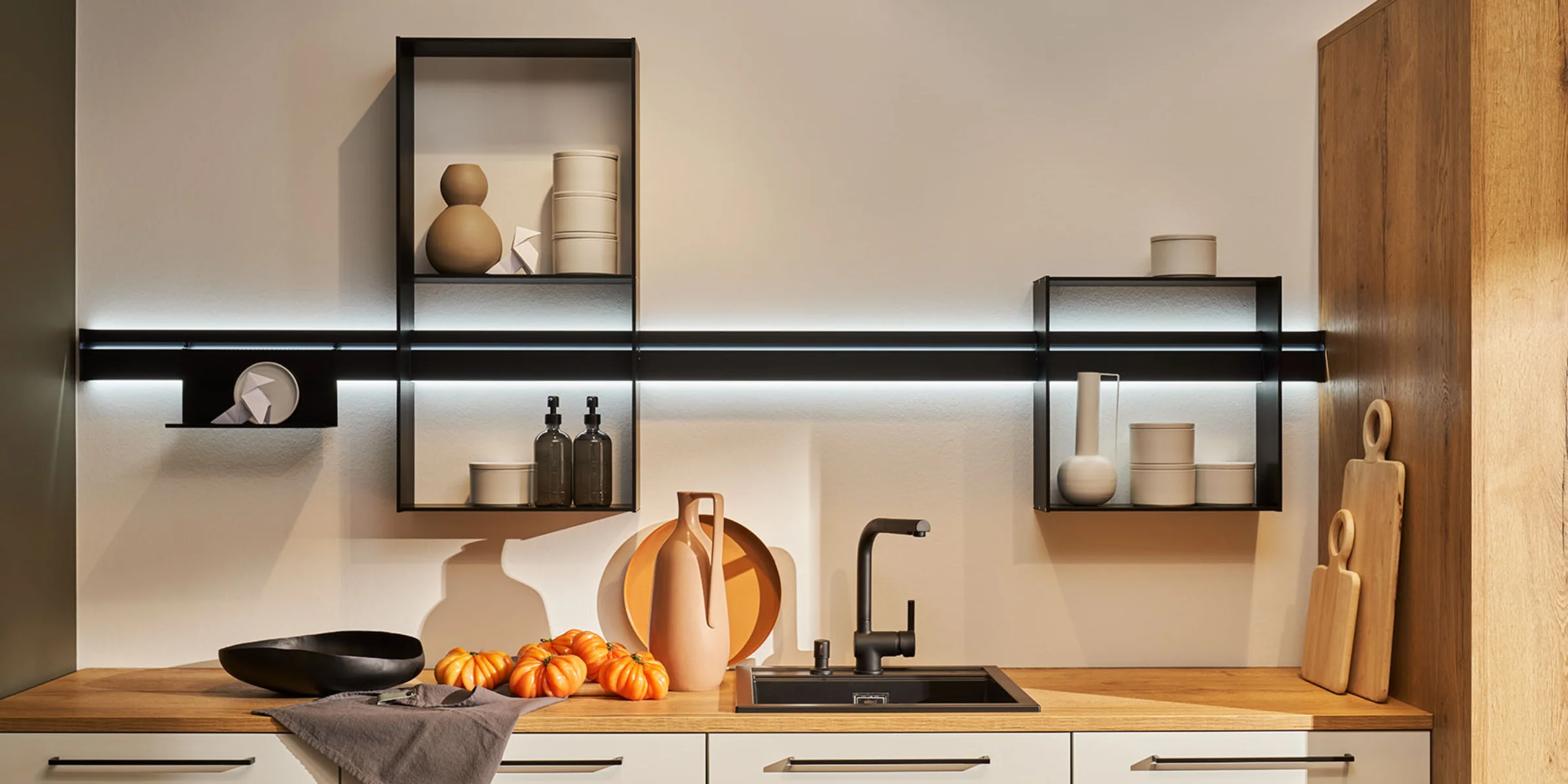 Eine moderne Küche mit Holzarbeitsplatte und stilvollen Regalen, gestaltet von Nolte Küchen.
