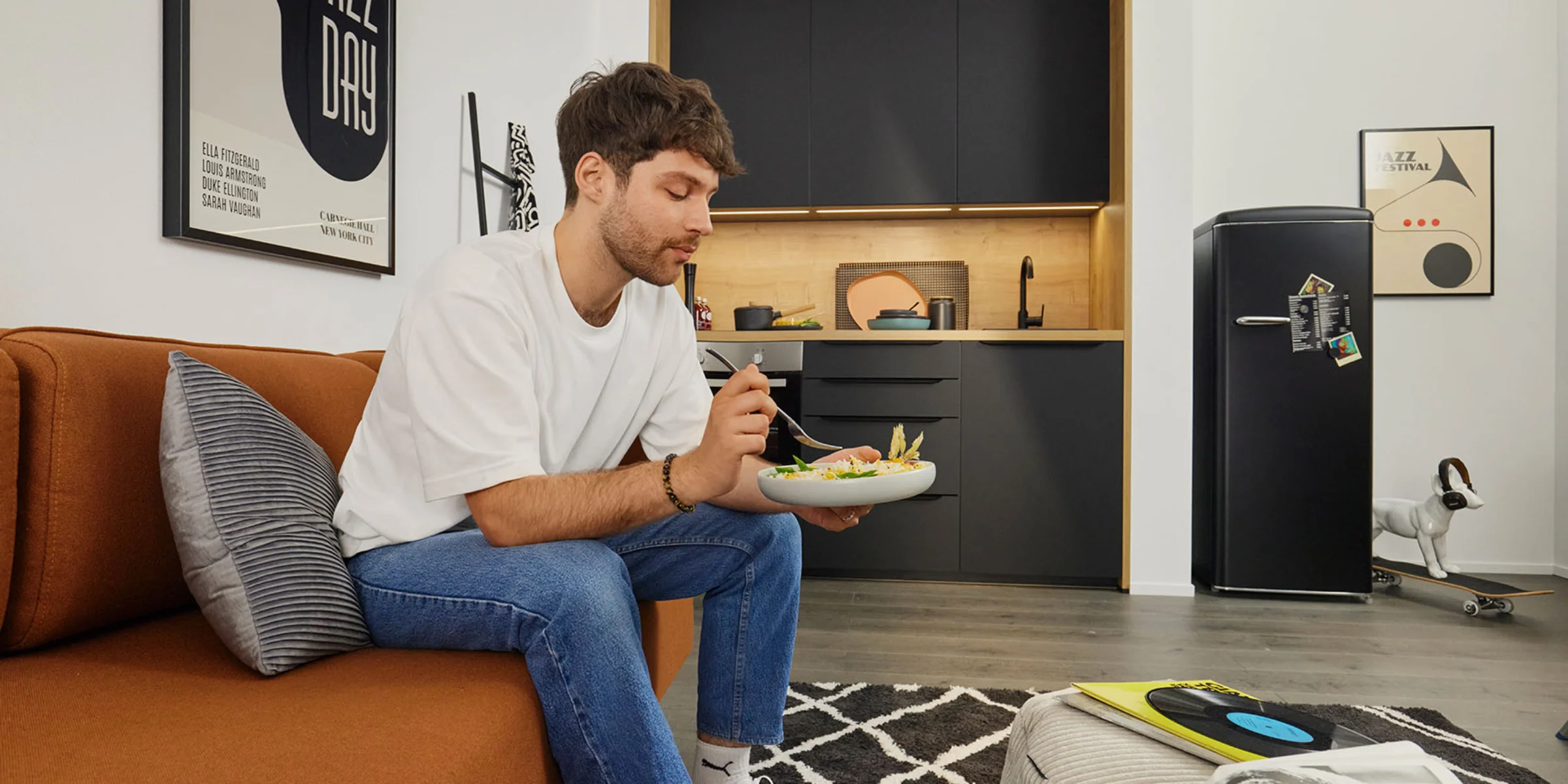 Un uomo mangia su un divano in una stanza con cucine Nolte.