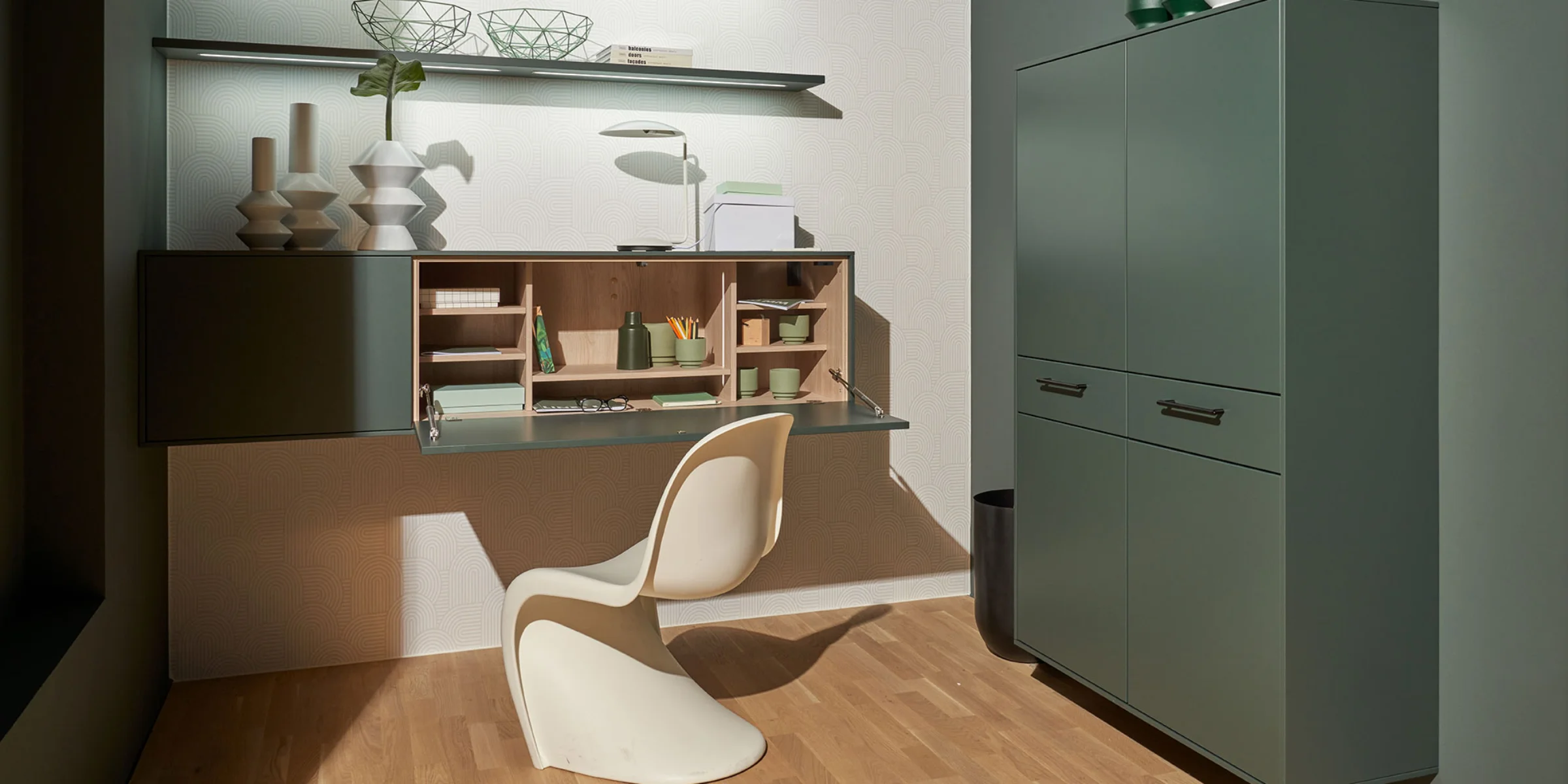 Ein eleganter Arbeitsbereich mit modernem Regal und Schrank in Grün, Teil von Nolte Living.