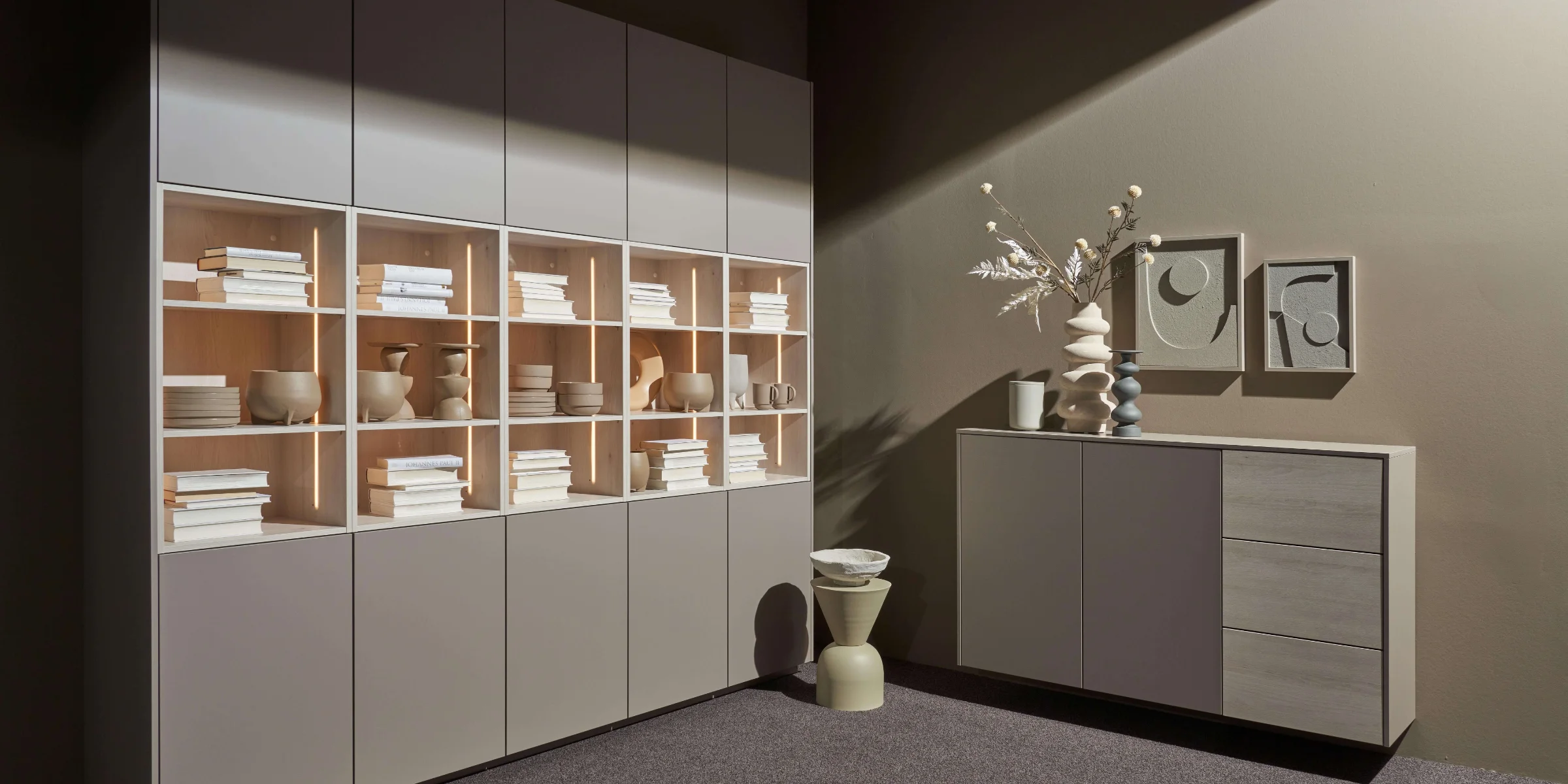 Ein Wohnzimmer mit modernen Regalen und Sideboard, dekoriert mit Vasen und Büchern, von Nolte Living.