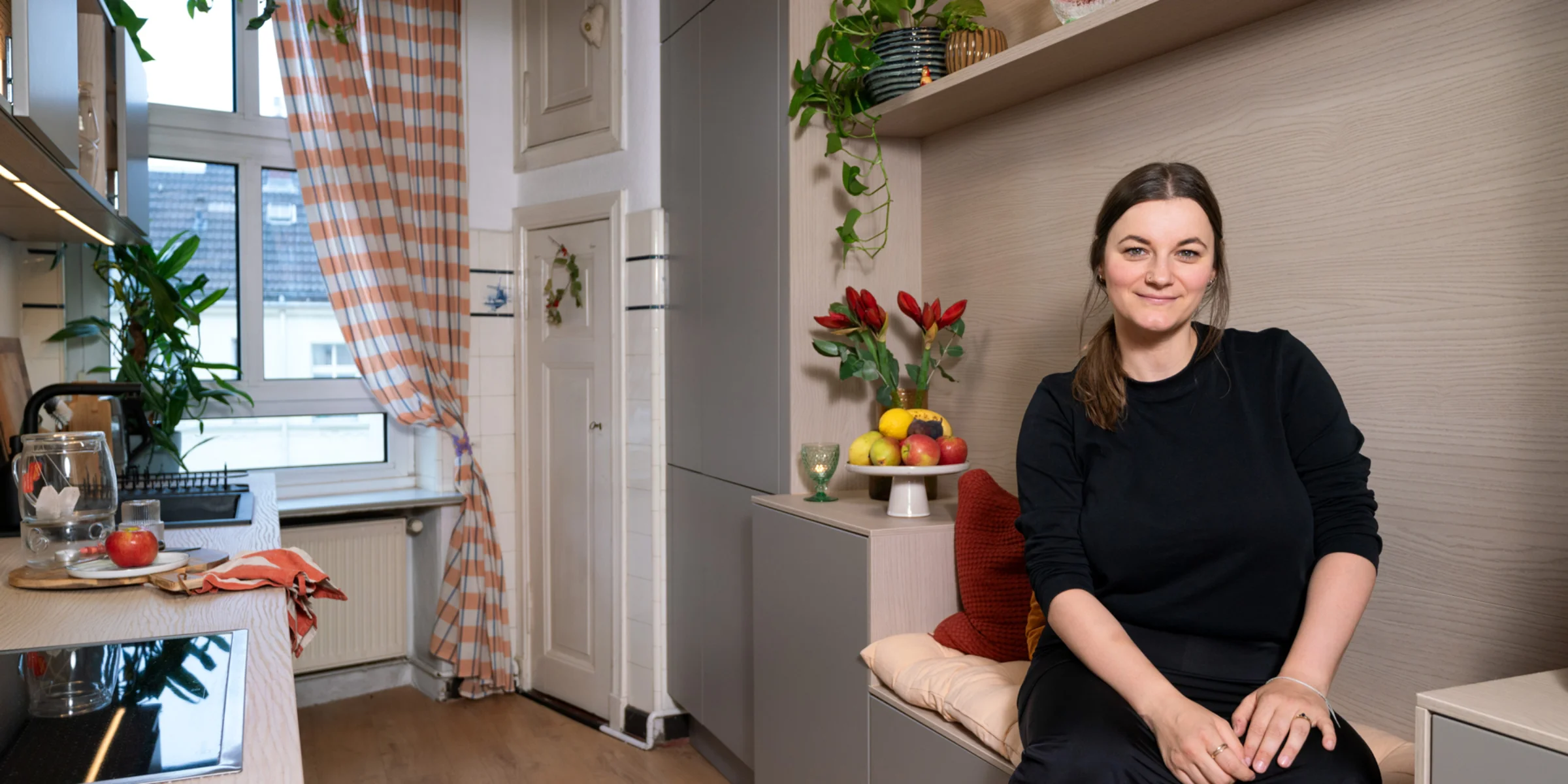 Eine Frau sitzt in einer modernen Küche mit Pflanzen, Design von Nolte Küchen.