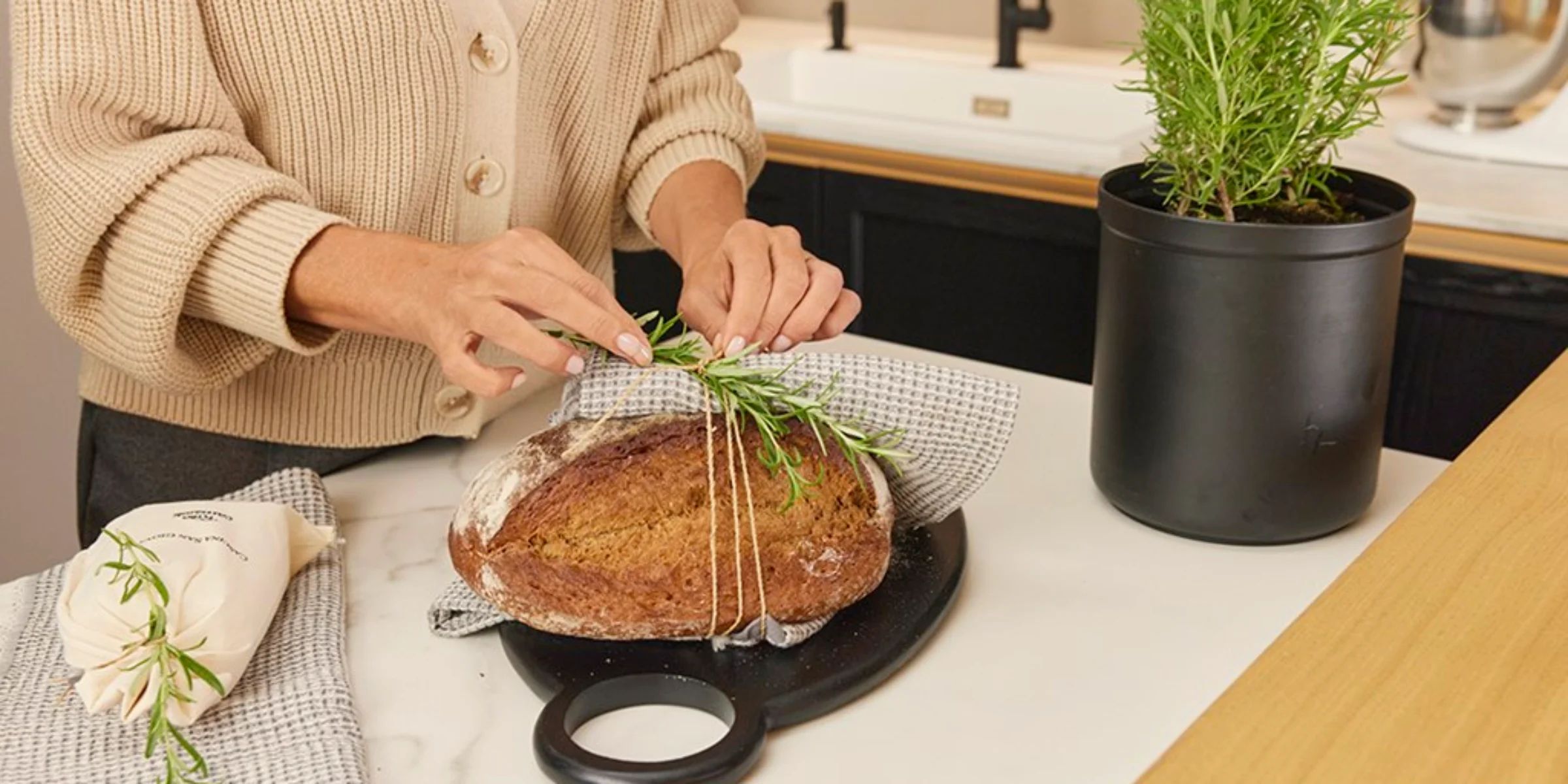 Eine Person bindet Rosmarin an ein Brot in einer modernen Küche von Nolte Küchen.
