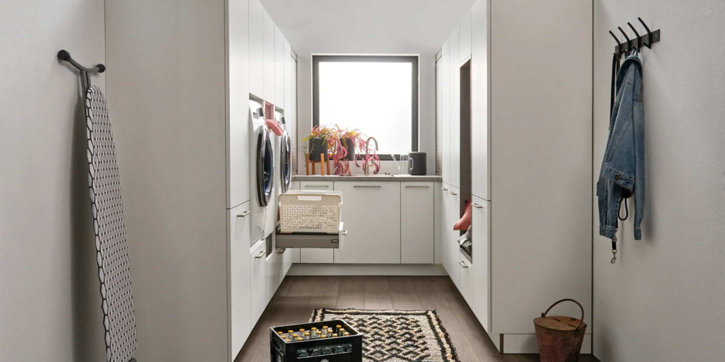 Buanderie de Nolte Küchen, avec le programme de façades FEEL en blanc soft mat, beaucoup d’espace de rangement, niche pour appareils, panier coulissant et design moderne.