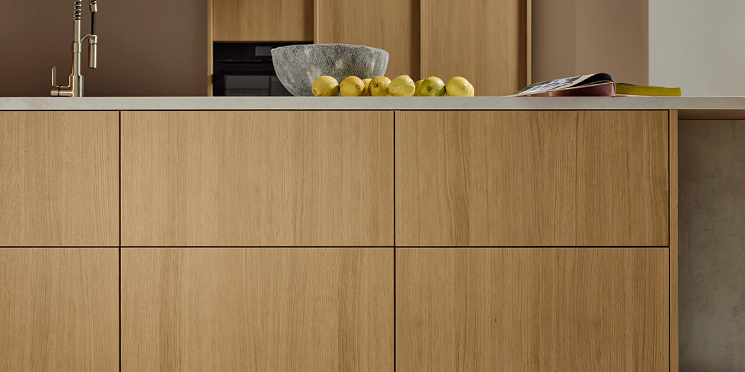 Moderne Küche mit Holzfronten und heller Arbeitsplatte, dekoriert mit Schale und Obst