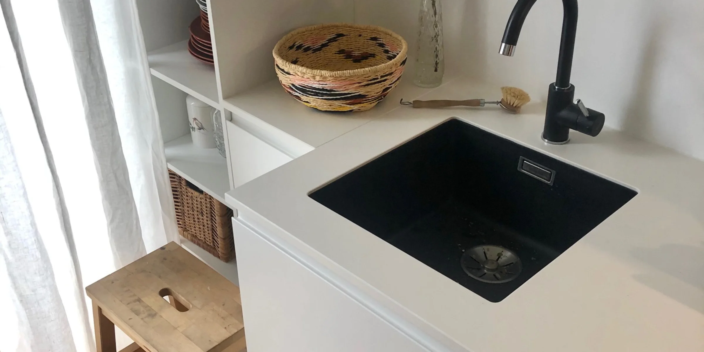 Eine moderne Küche mit weißem Waschtisch und Regal, dekoriert mit Pflanzen. Nolte Küchen.